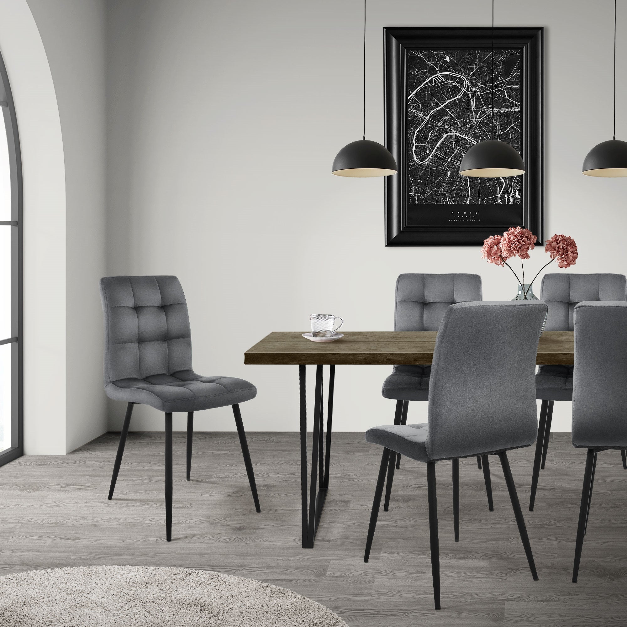 Esszimmer mit grauen Stühlen um einen Tisch, dekoriert mit Blumen und einem Bild.