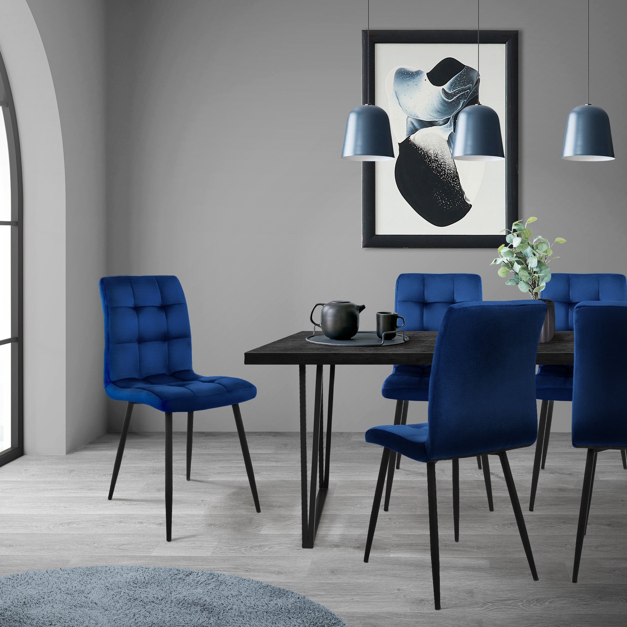 Ein blauer Stuhl und ein Tisch in einem Raum mit Pendelleuchten und Pflanzen.