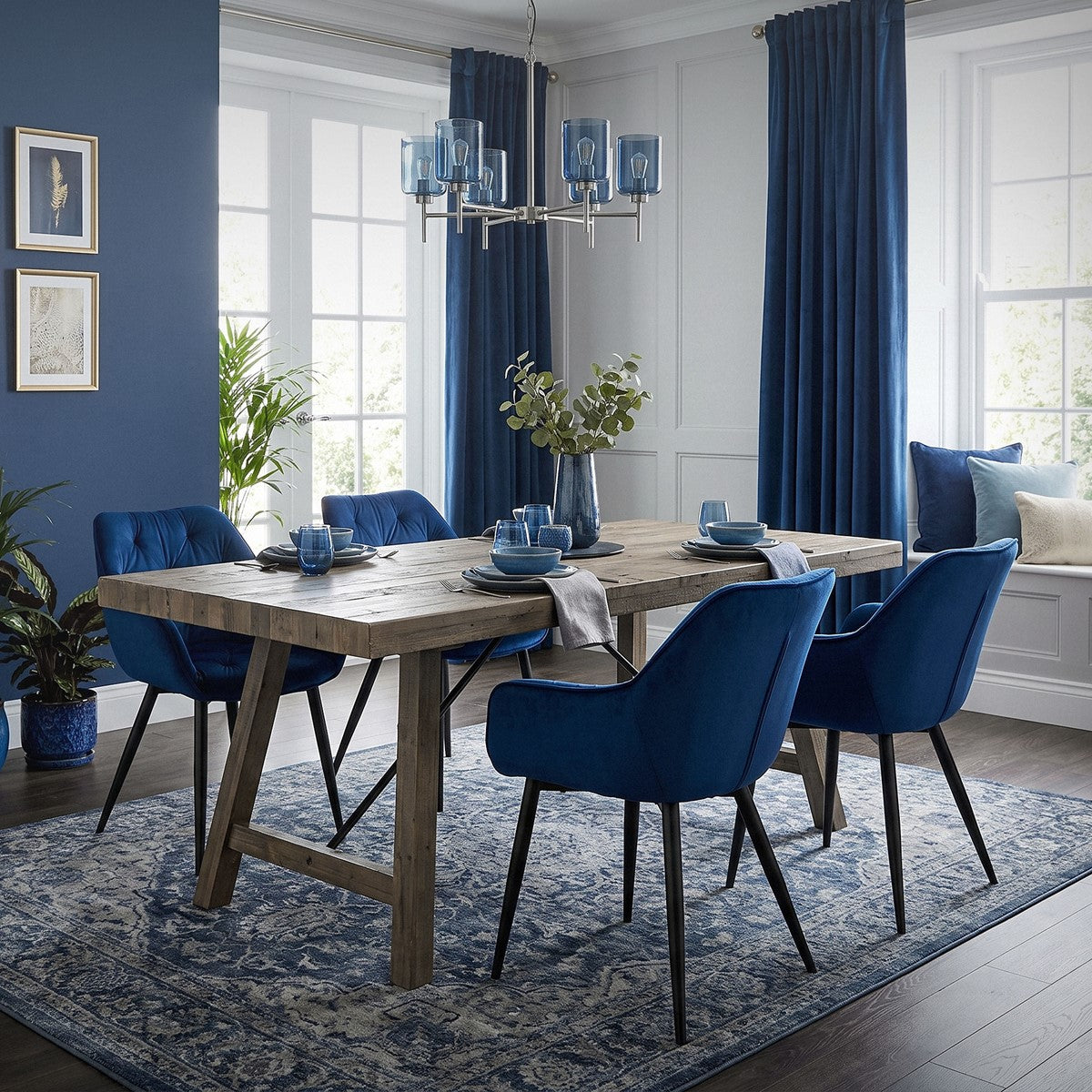 Ein Esszimmer mit einem Holztisch und blauen Stühlen, dekoriert mit Pflanzen.