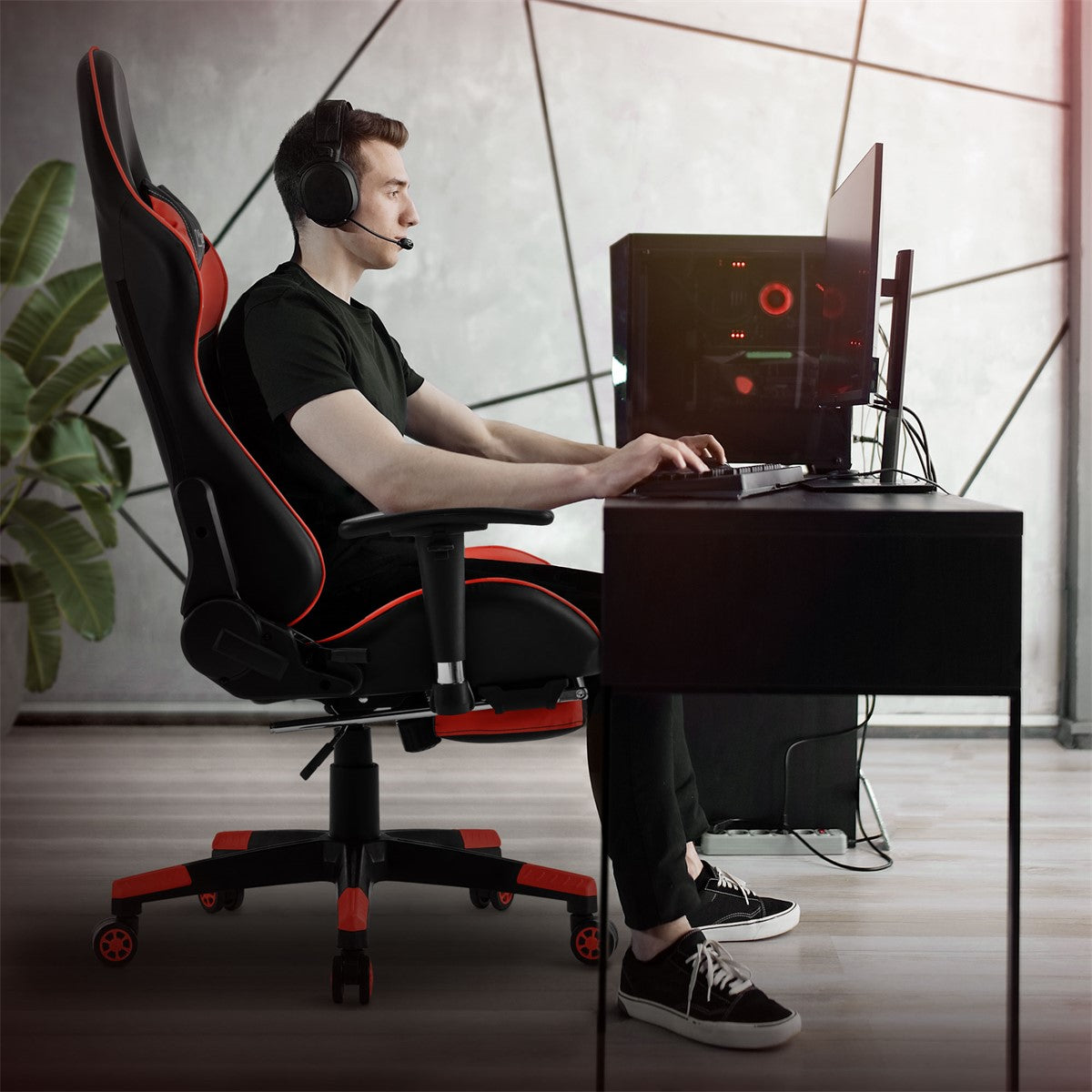 Junger Mann sitzt an einem Schreibtisch mit Gaming-Stuhl und Computer.