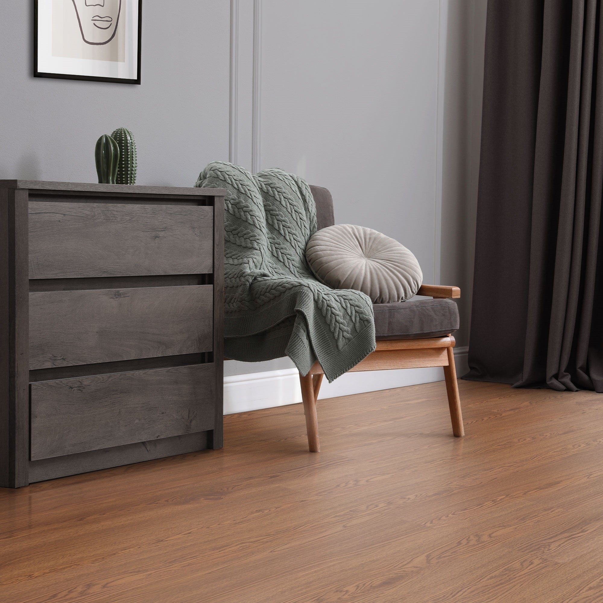 A cozy room with an armchair, a blanket, and a wooden floor.