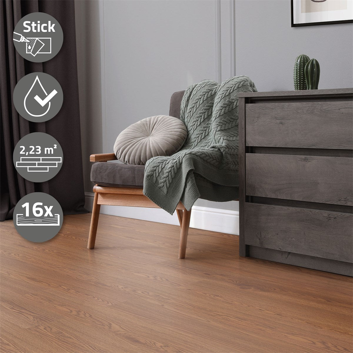A gray armchair with a blanket, a cushion, and a cabinet in a room.