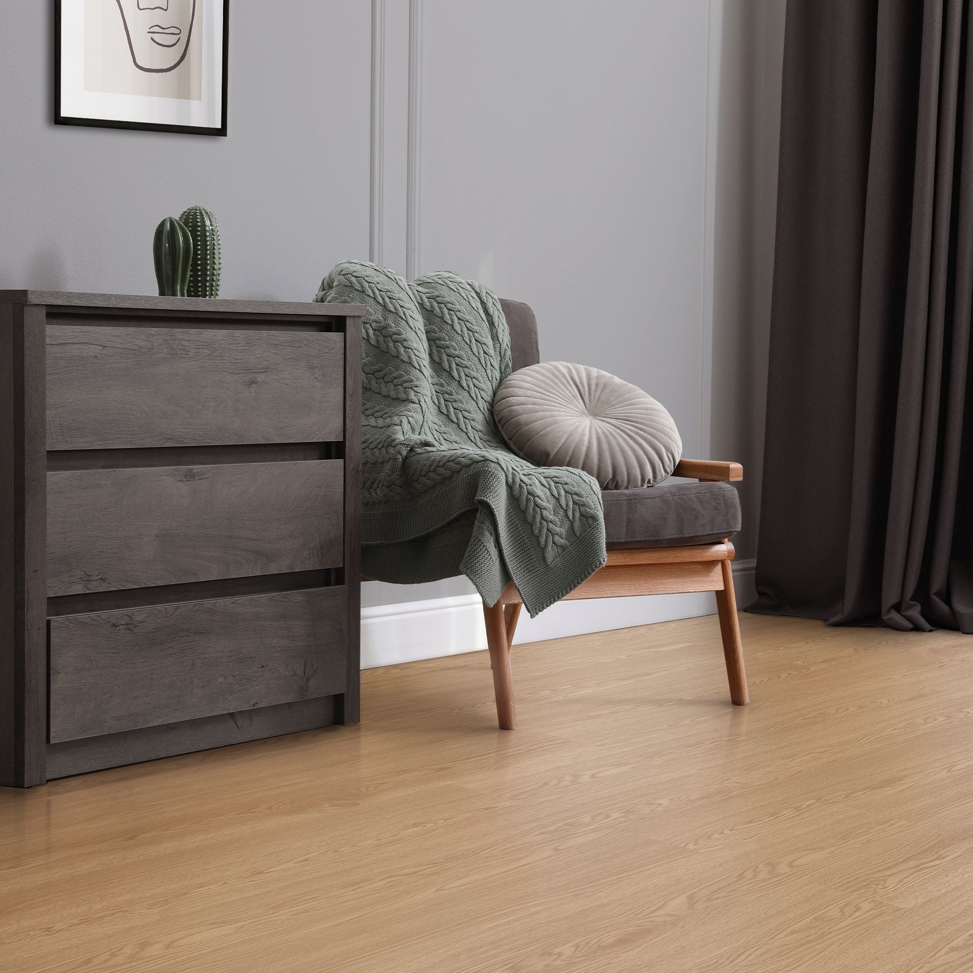 Wohnzimmer mit grauem Sessel, Kissen und einer Kommode.