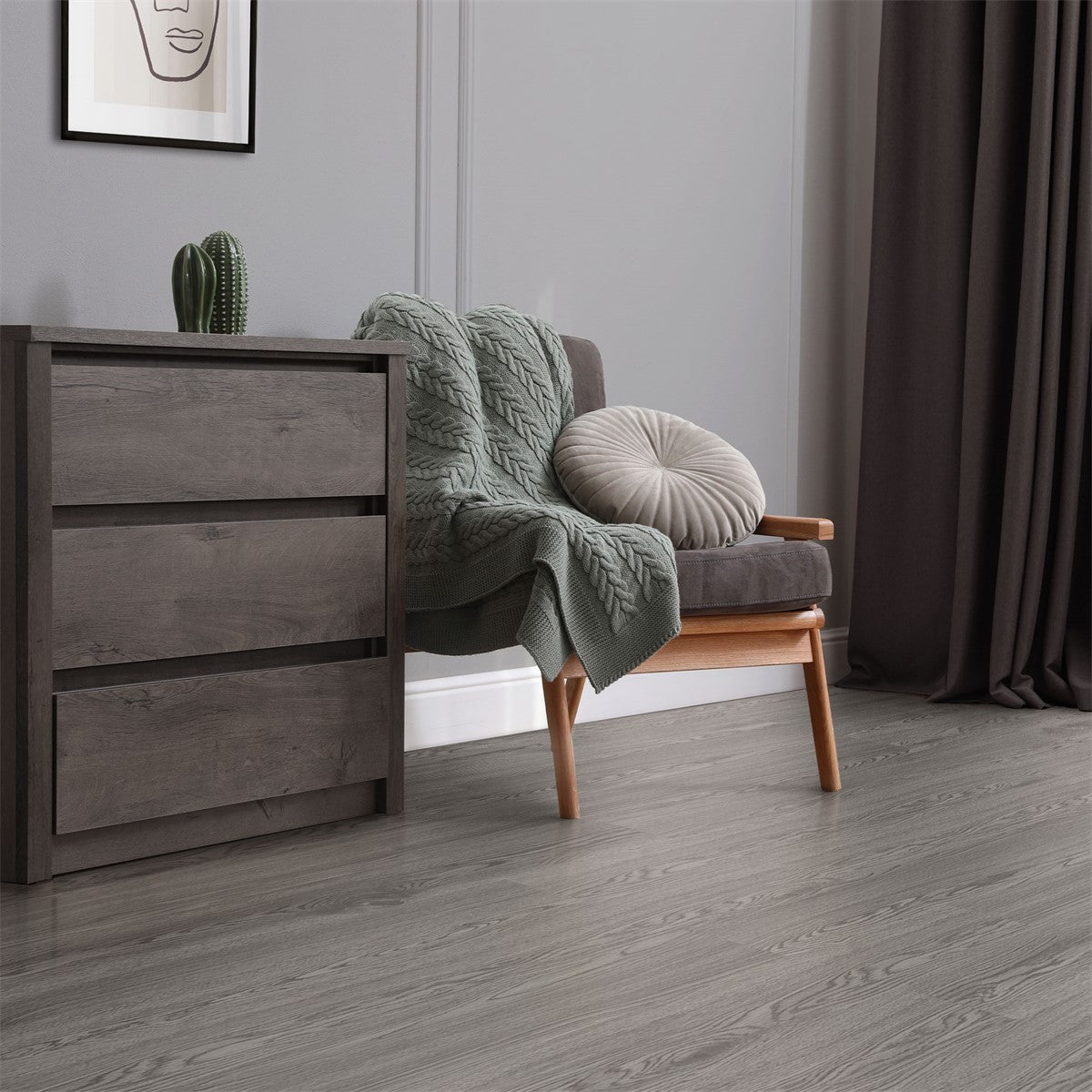 Wohnzimmer mit grauem Boden, Sessel, Kissen und Pflanze.