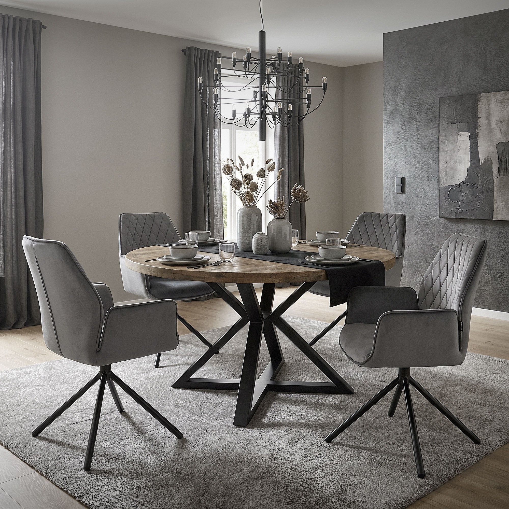 Esszimmer mit runder Holzplatte und vier grauen Stühlen.