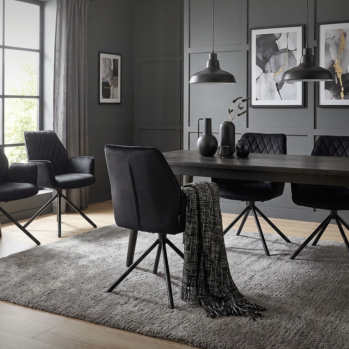 Uma área de refeições com uma mesa, cadeiras pretas e quadros decorativos na parede.