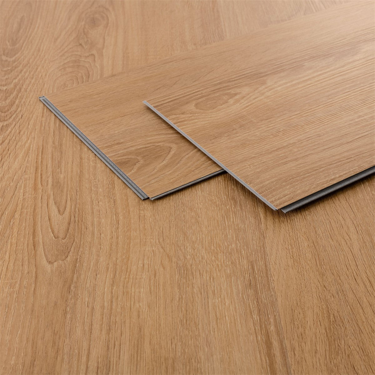 Zwei Laminatplatten in Holzoptik auf einem hellen Holzfußboden.