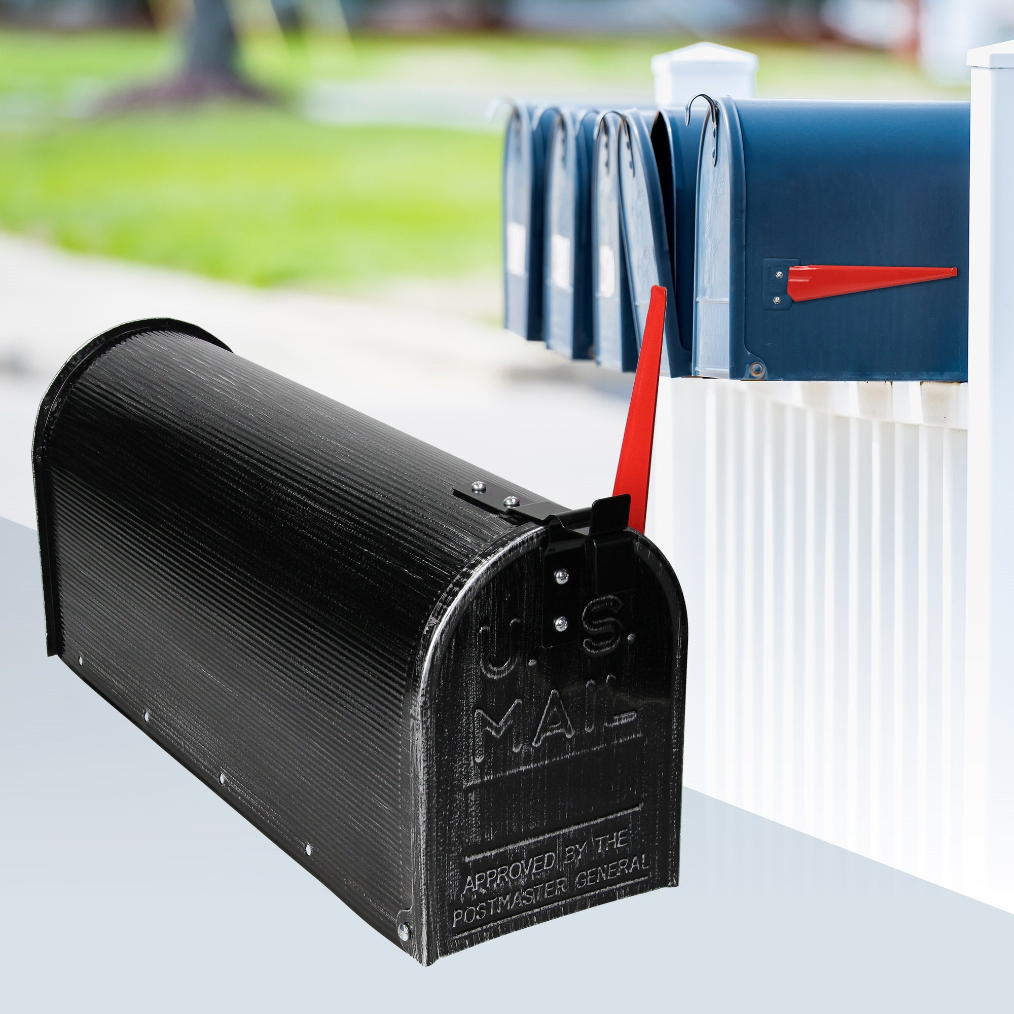 Schwarzer Briefkasten mit rotem Fahnenhebel neben blauen Briefkästen.