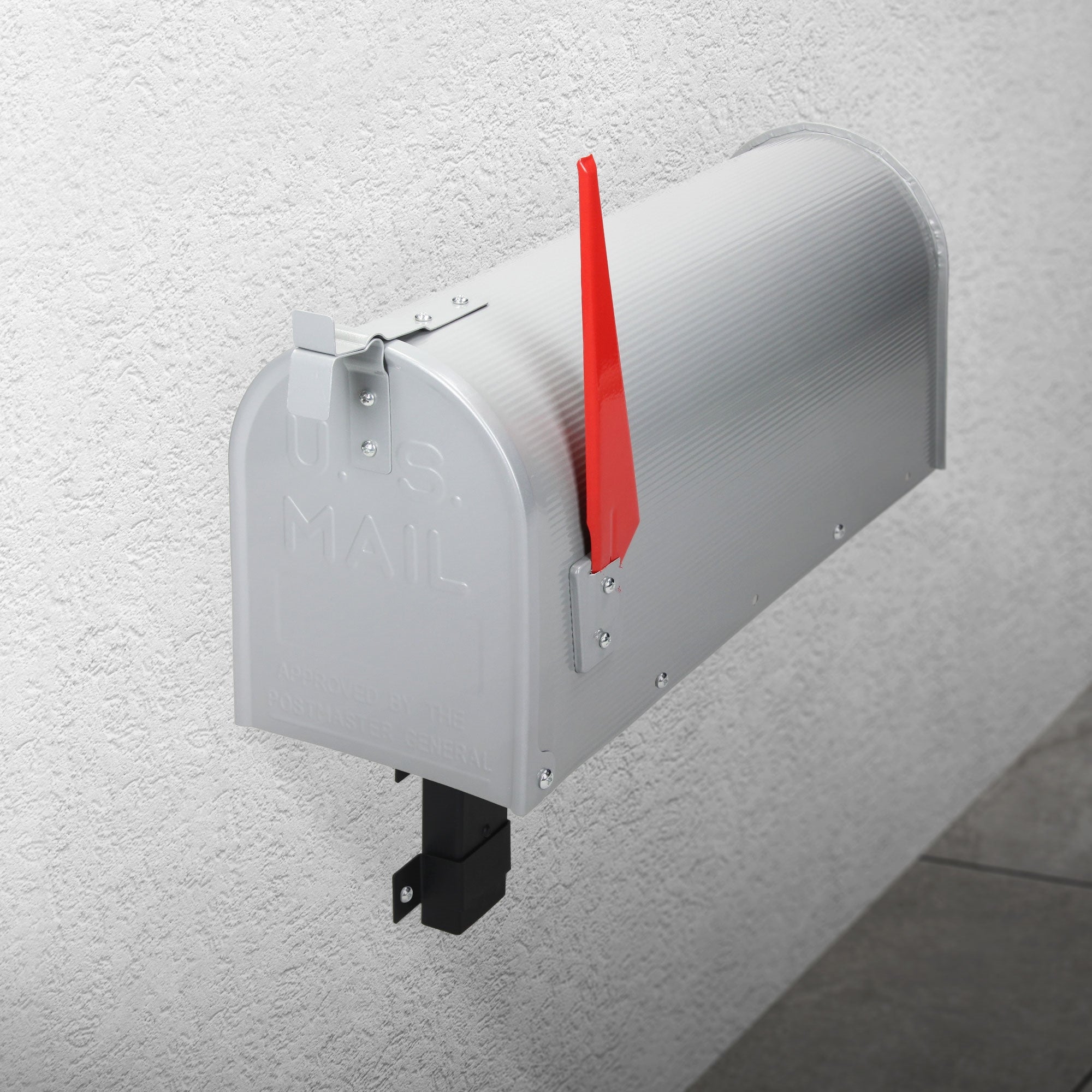 Silver mailbox on a wall with a red flag sign.