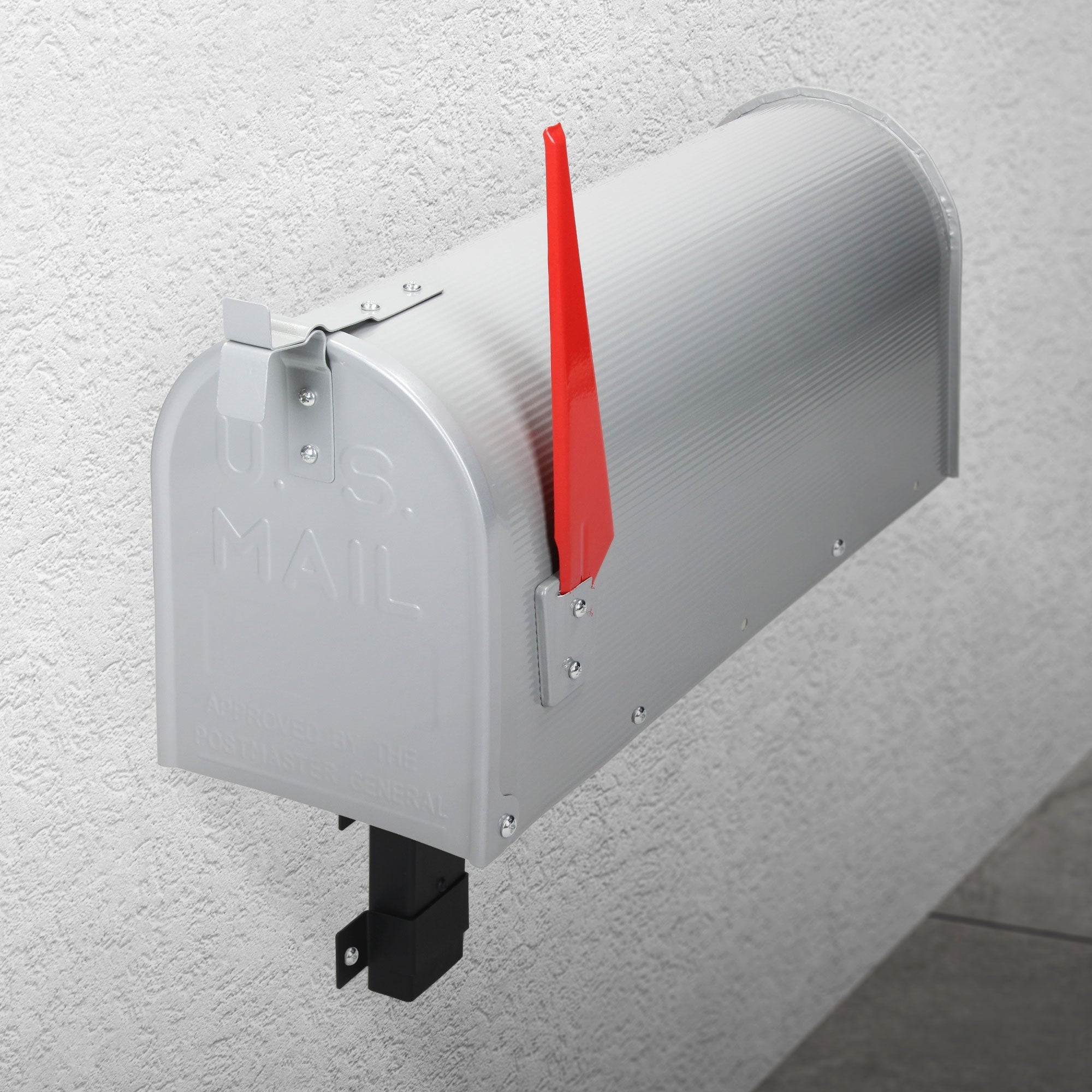 Silver mailbox on a wall with a red flag lever.
