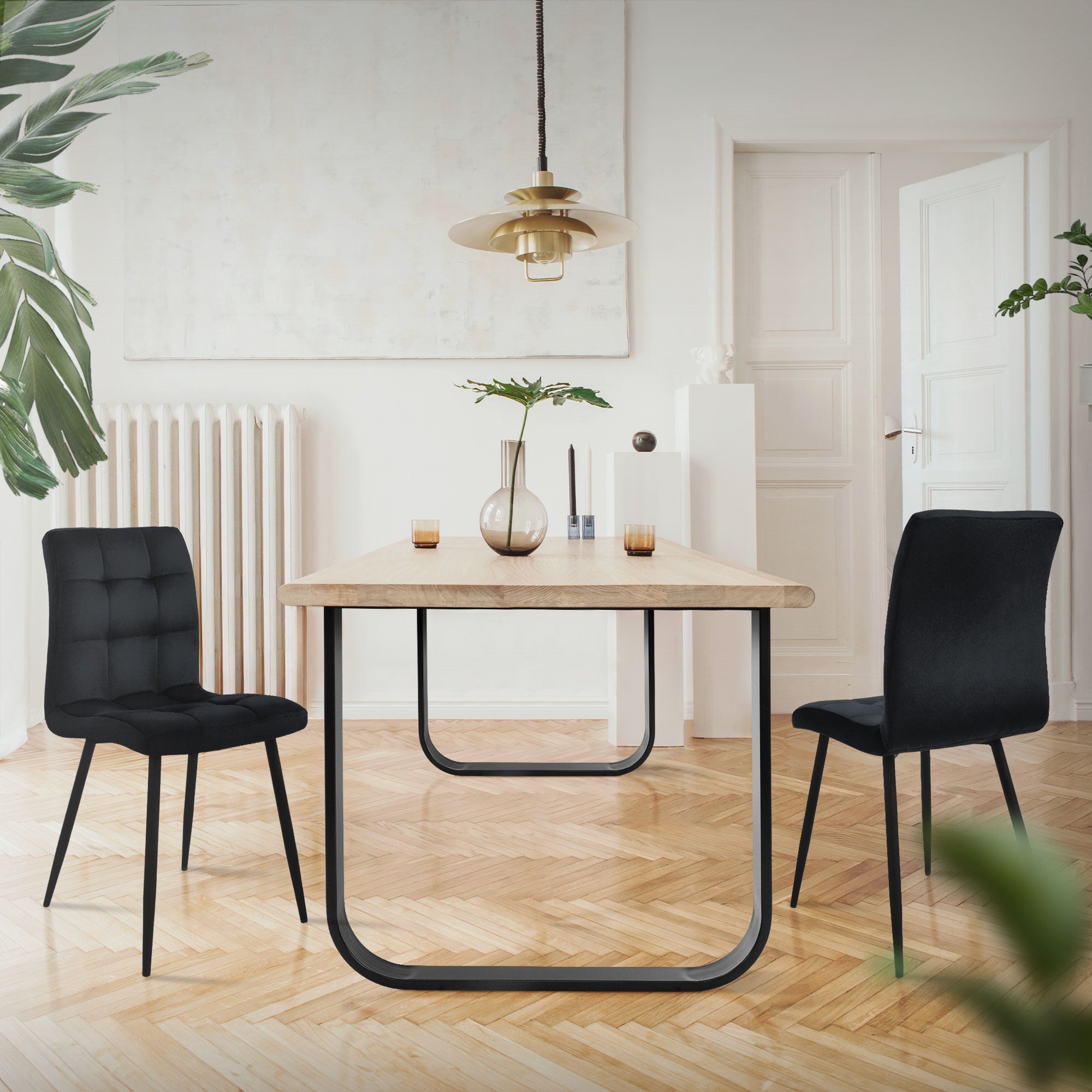 A dining room with a table and two chairs in a bright room.