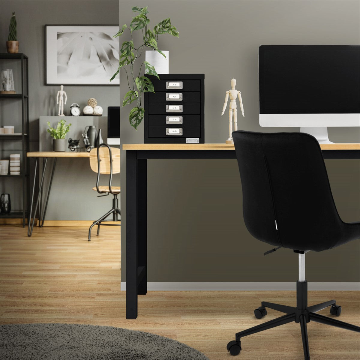 Büro mit schwarzem Aktenschrank, Computer und Pflanze auf dem Tisch.