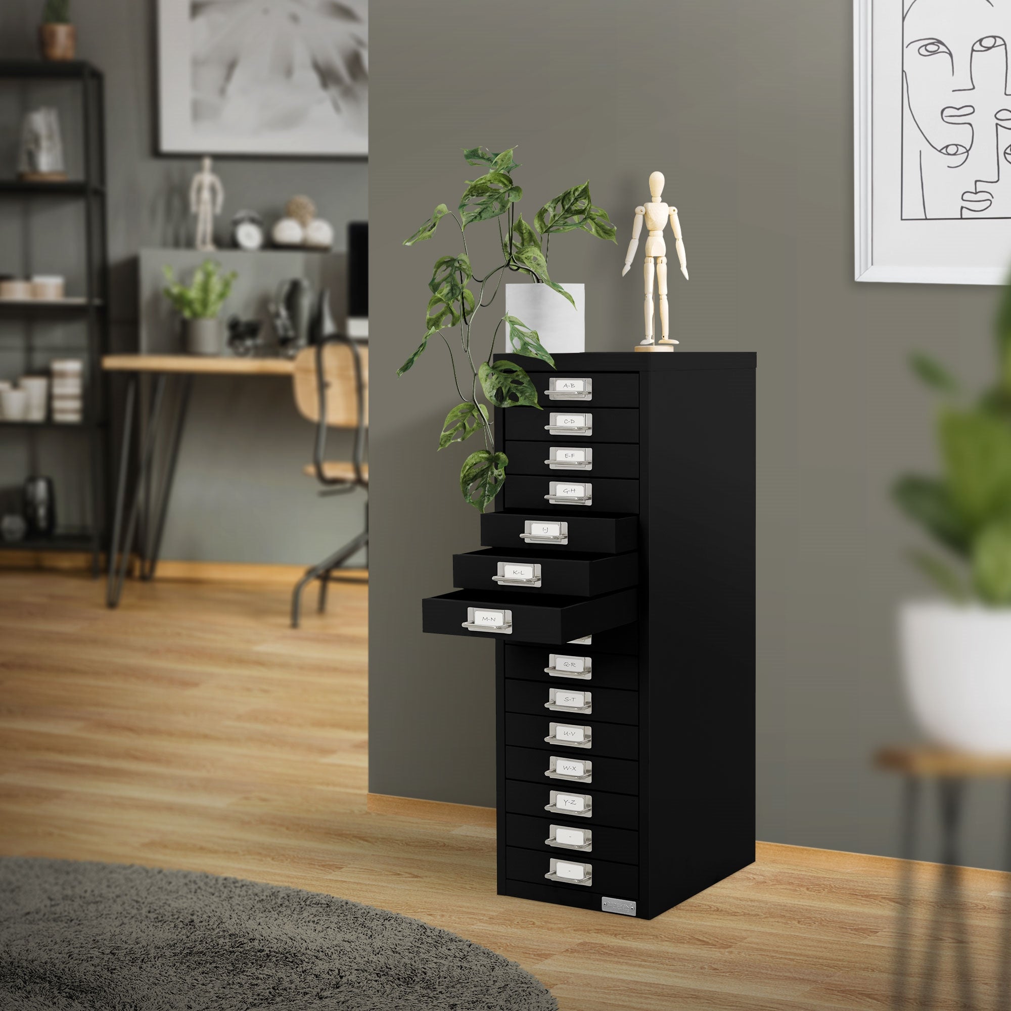 Schwarzer Schubladenschrank in einem modernen Raum mit Pflanzen und einem Holzfußboden.