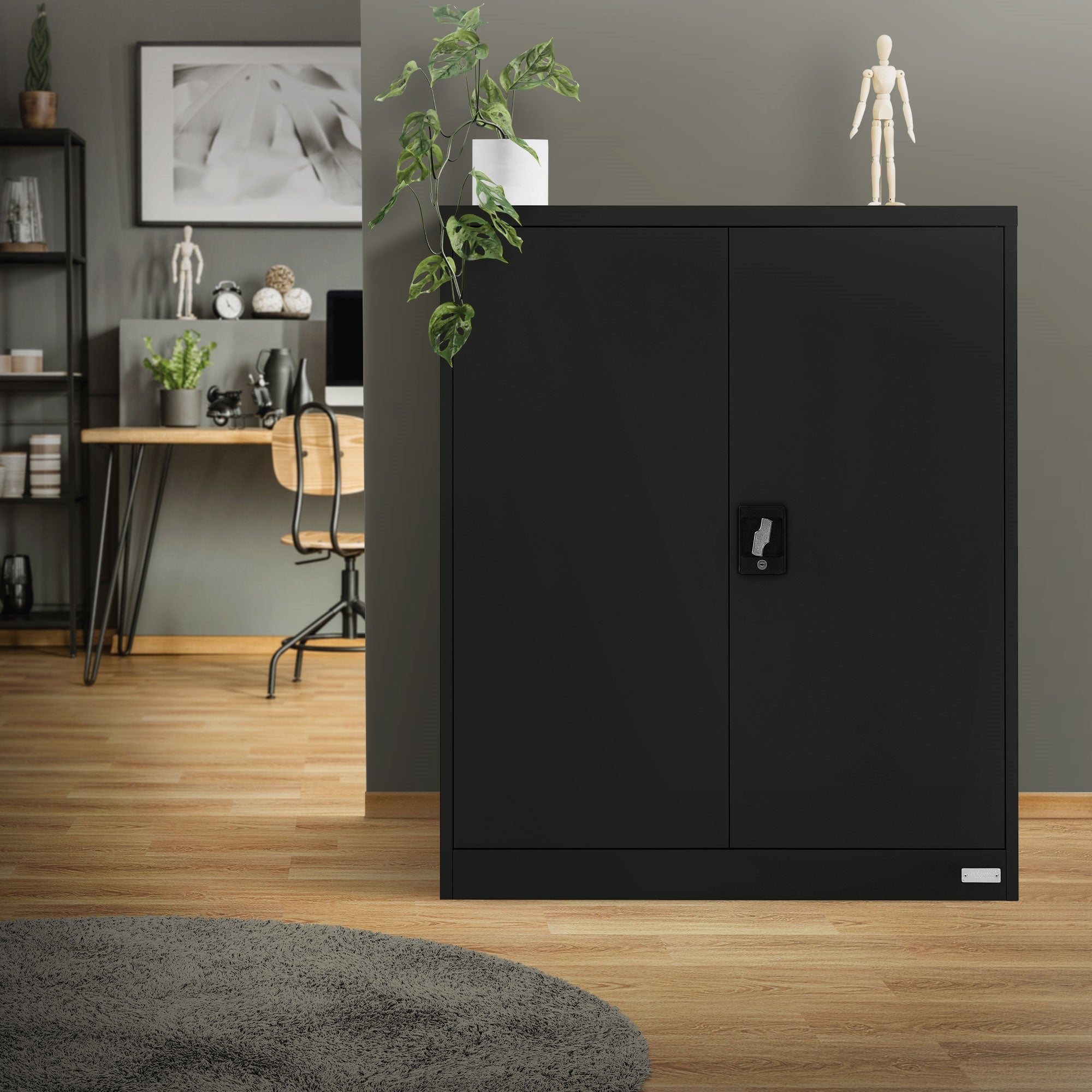 Schwarzer Schrank mit zwei Türen in einem Raum mit Holzfußboden und Pflanzen.