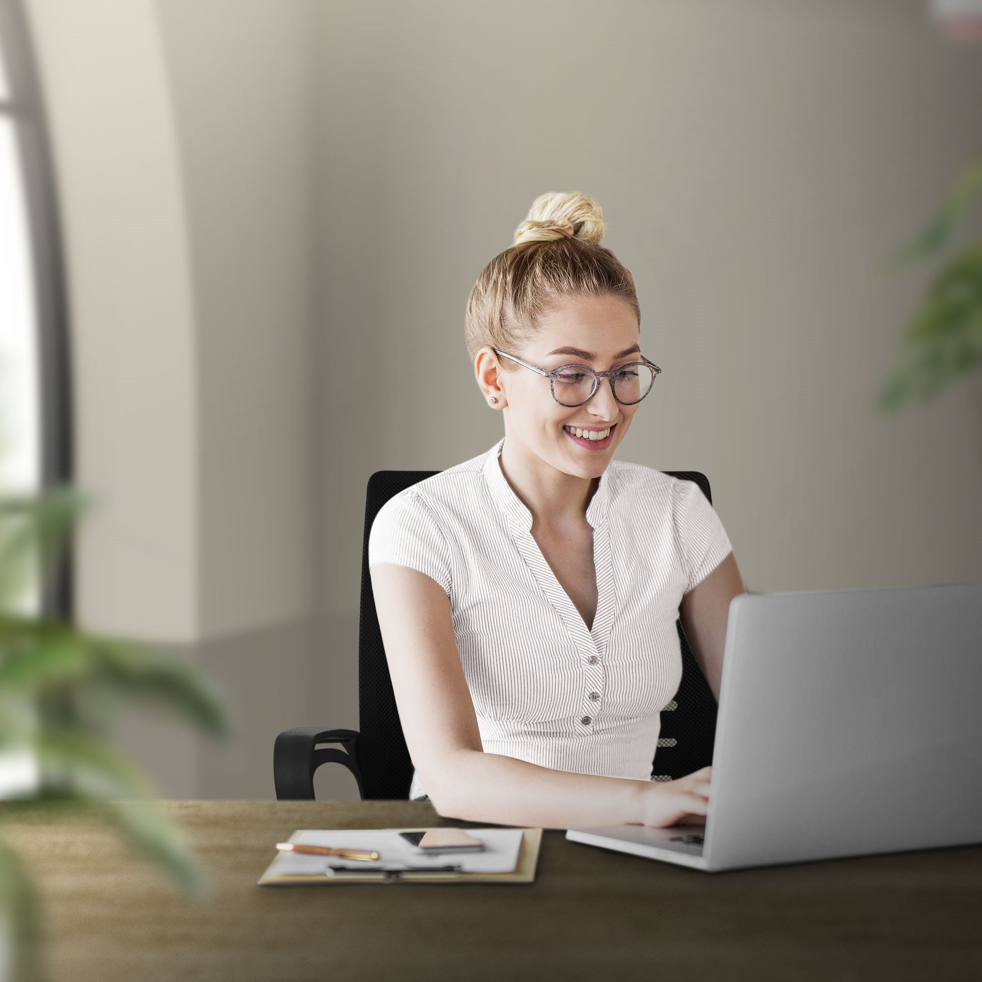 Frau lächelt, während sie am Laptop arbeitet, umgeben von Pflanzen.