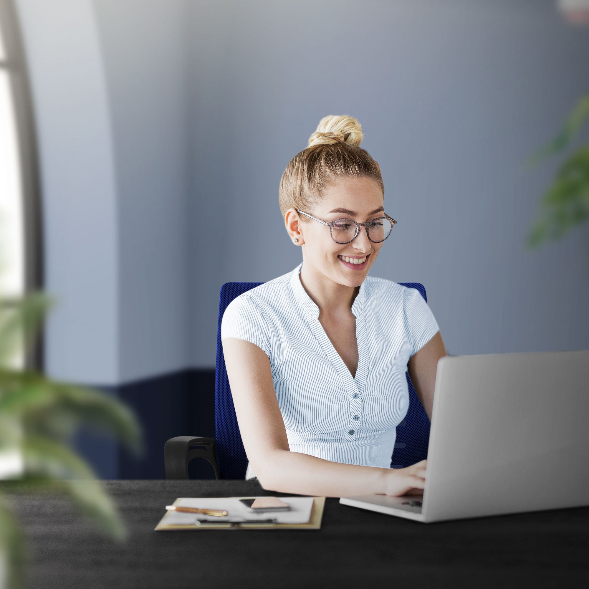 Donna sorridente al laptop, seduta su una sedia da ufficio blu.