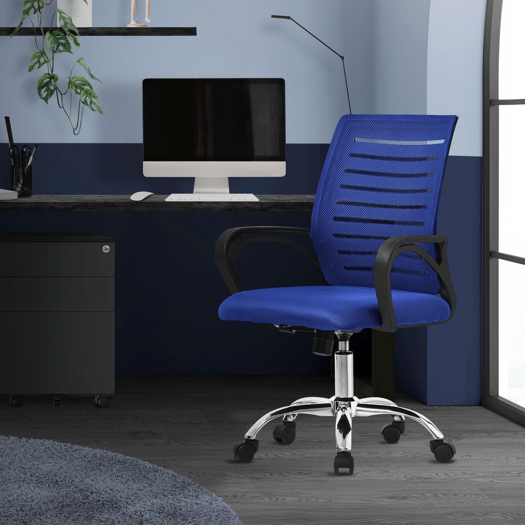 Sedia da ufficio blu davanti a una scrivania con computer in una stanza moderna.
