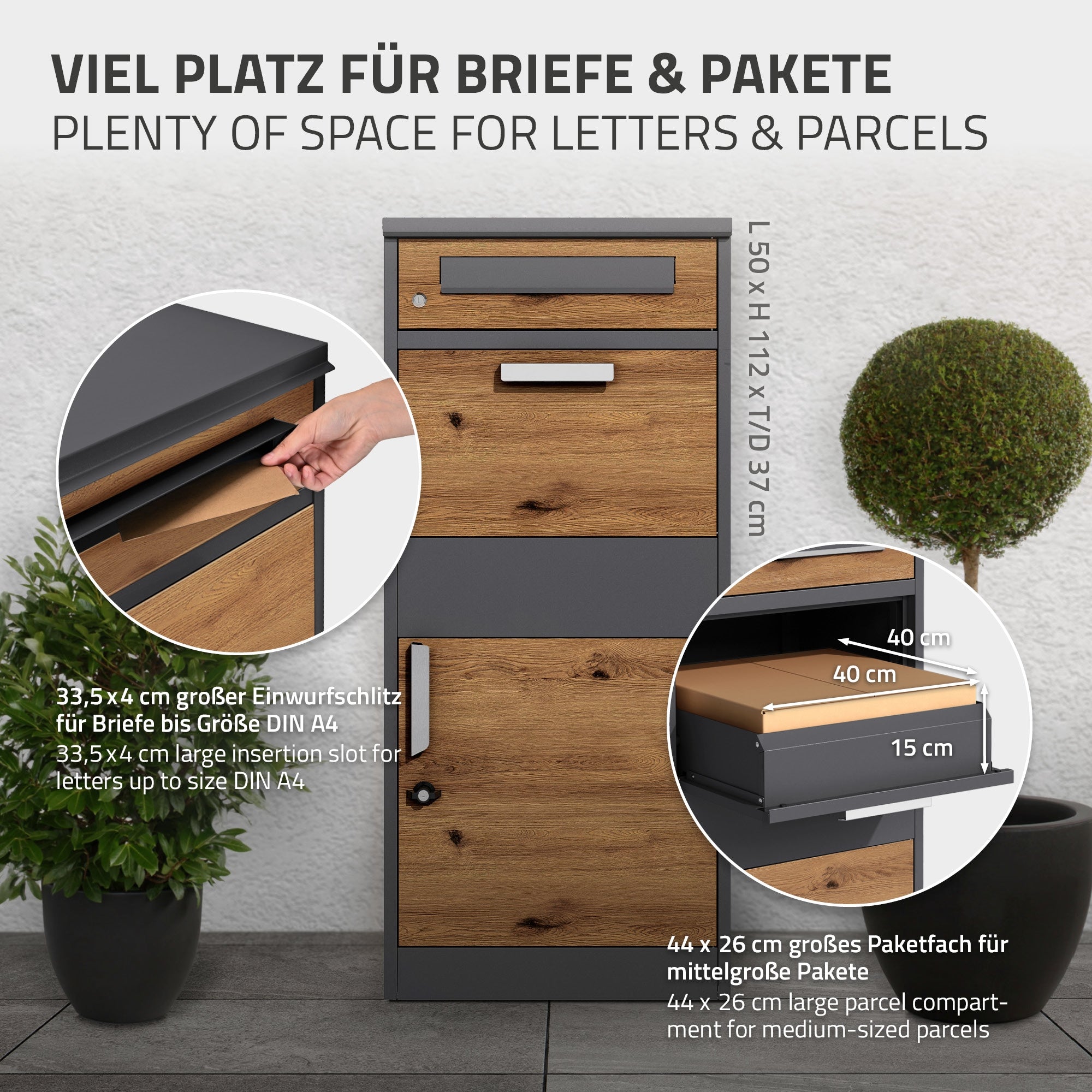 Briefkasten mit Fächern für Briefe und Pakete, Pflanzen im Hintergrund.