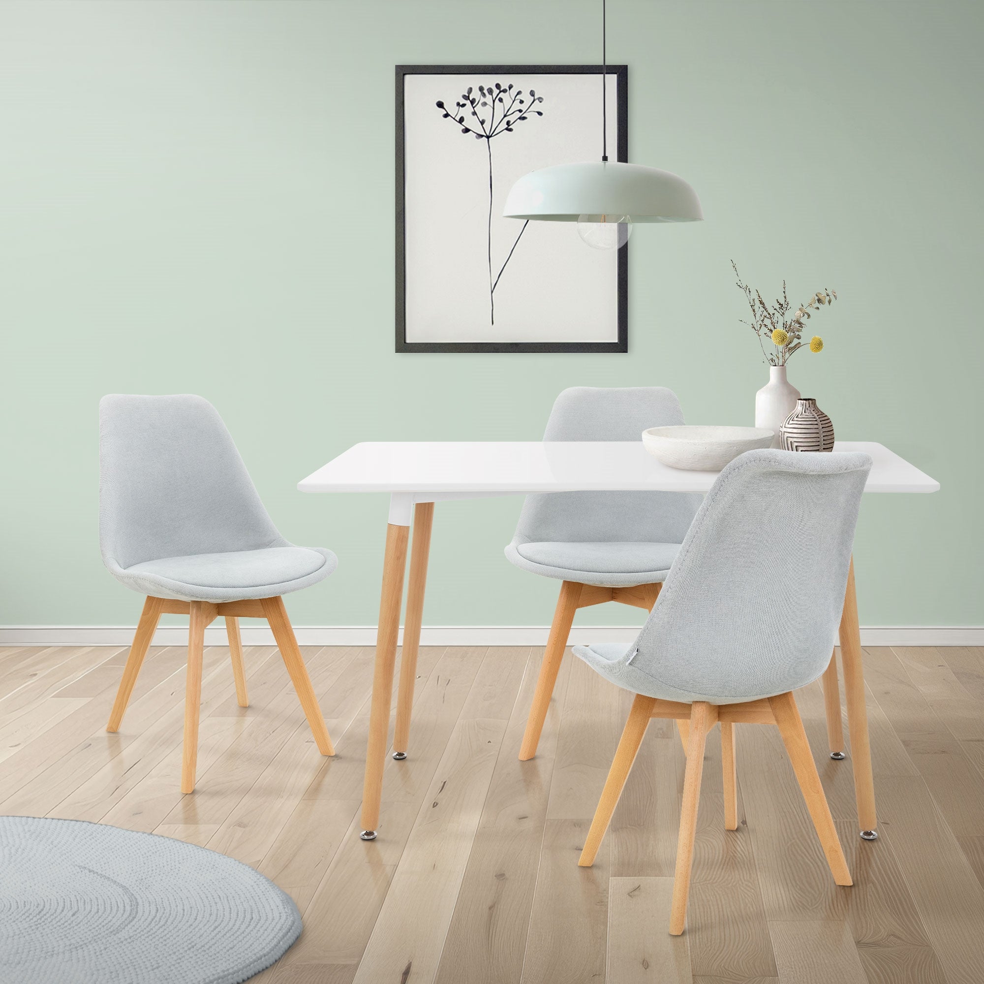 Bright room with a white table and gray chairs, decorated with a vase.