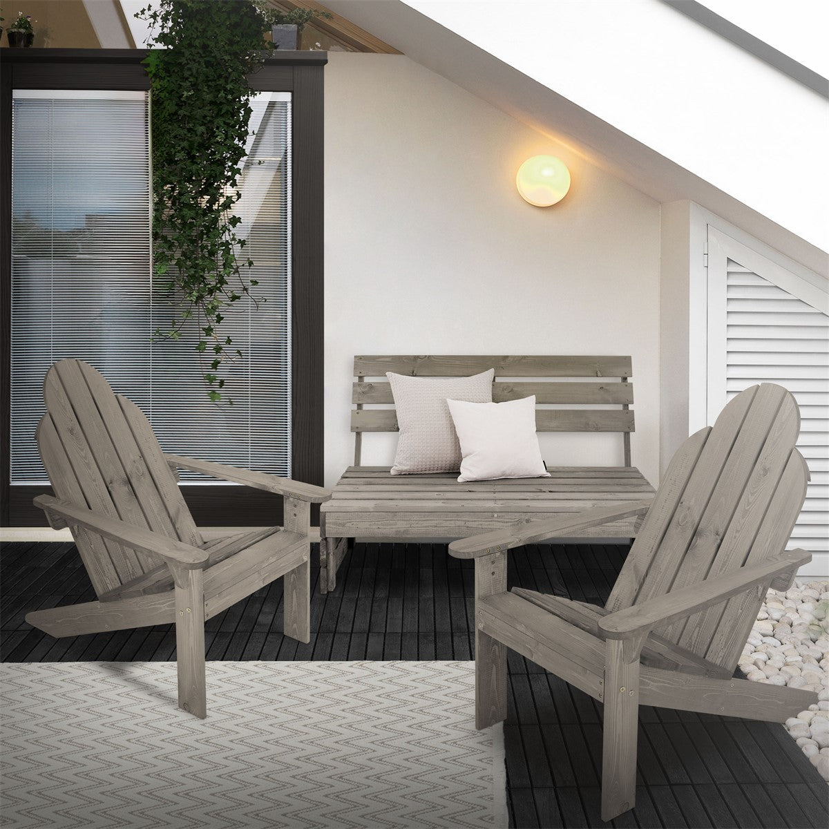 Two wooden chairs and a table on a terrace, with cushions and plants in the background