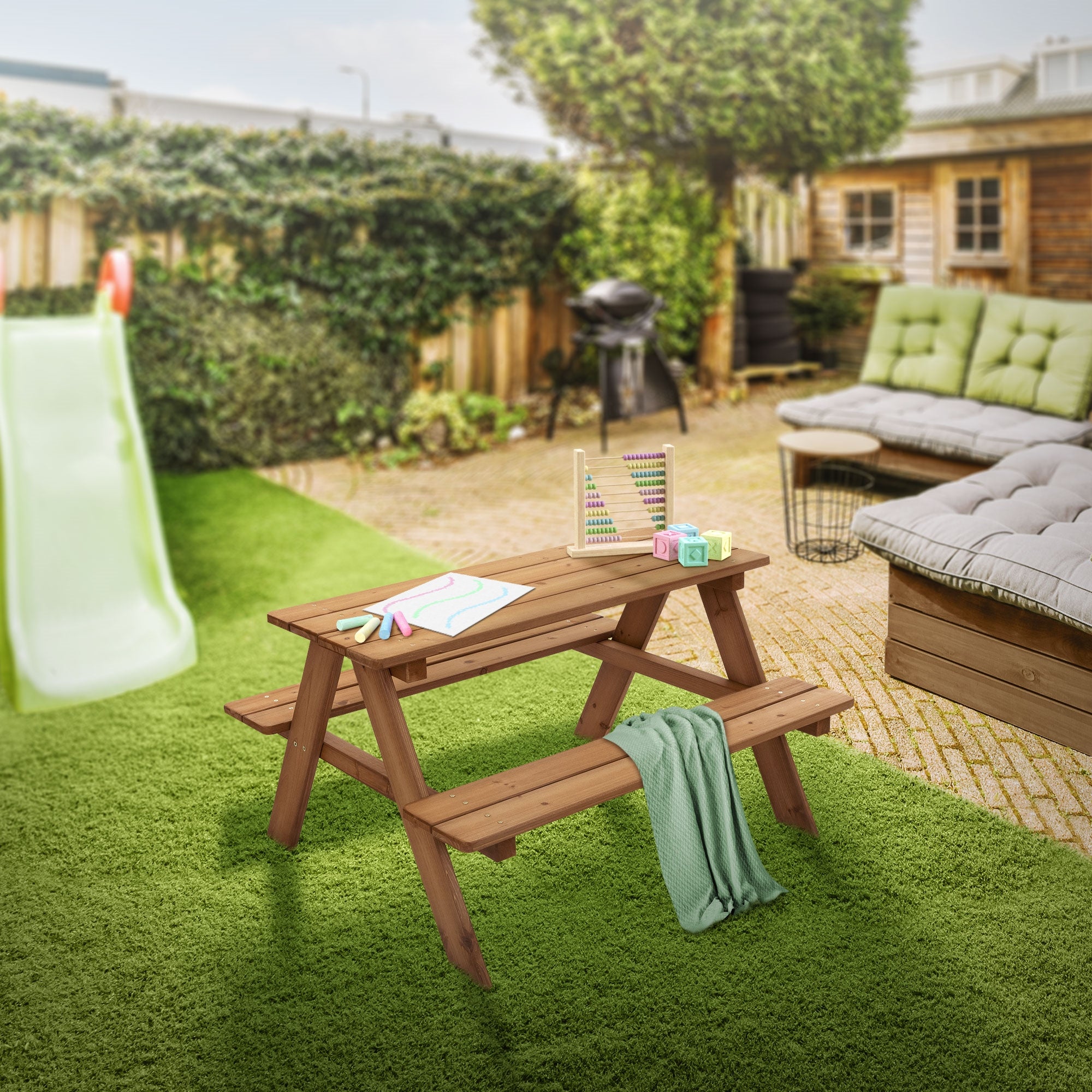 Holztisch im Garten mit Spielzeug und einer Rutsche im Hintergrund.