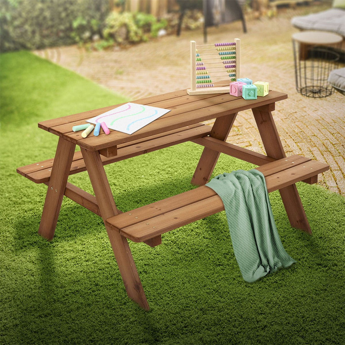 Wooden table with two benches outdoors, surrounded by lawn and toys.