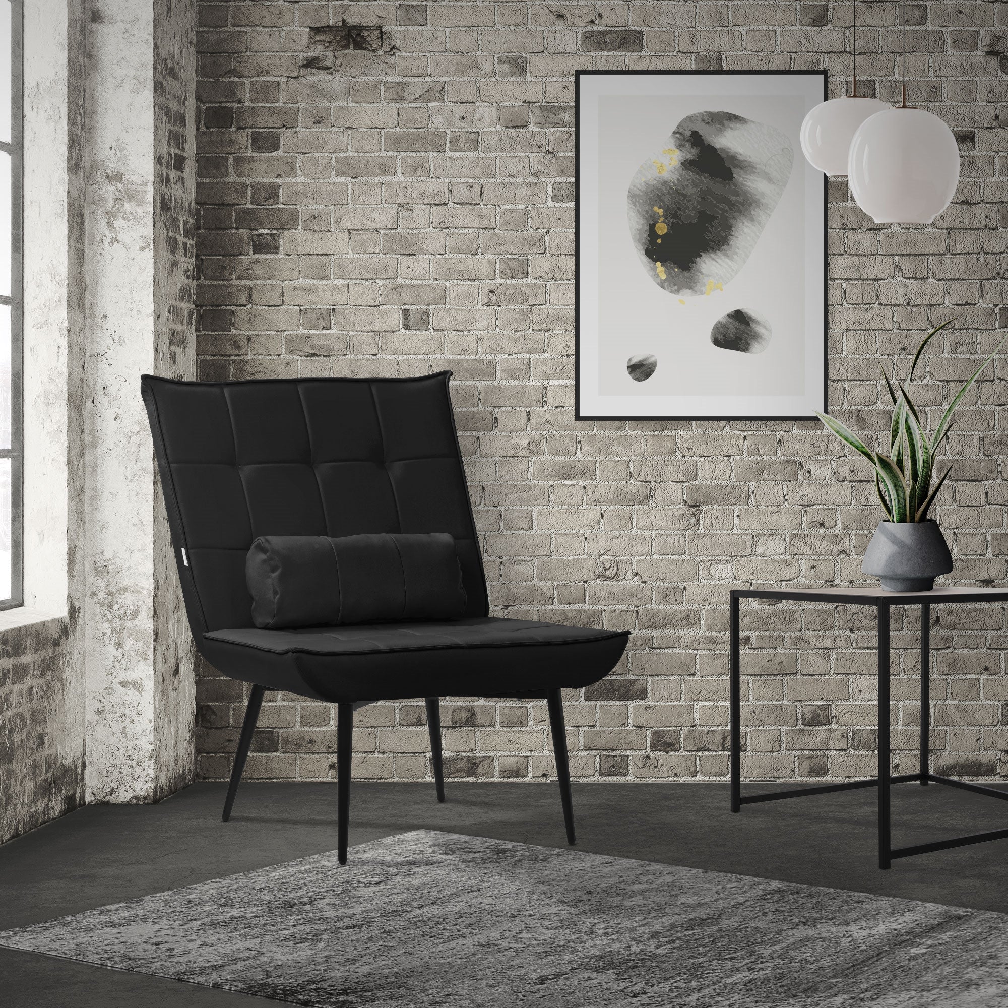 Un sillón negro frente a una pared de ladrillo con una obra de arte y una planta.