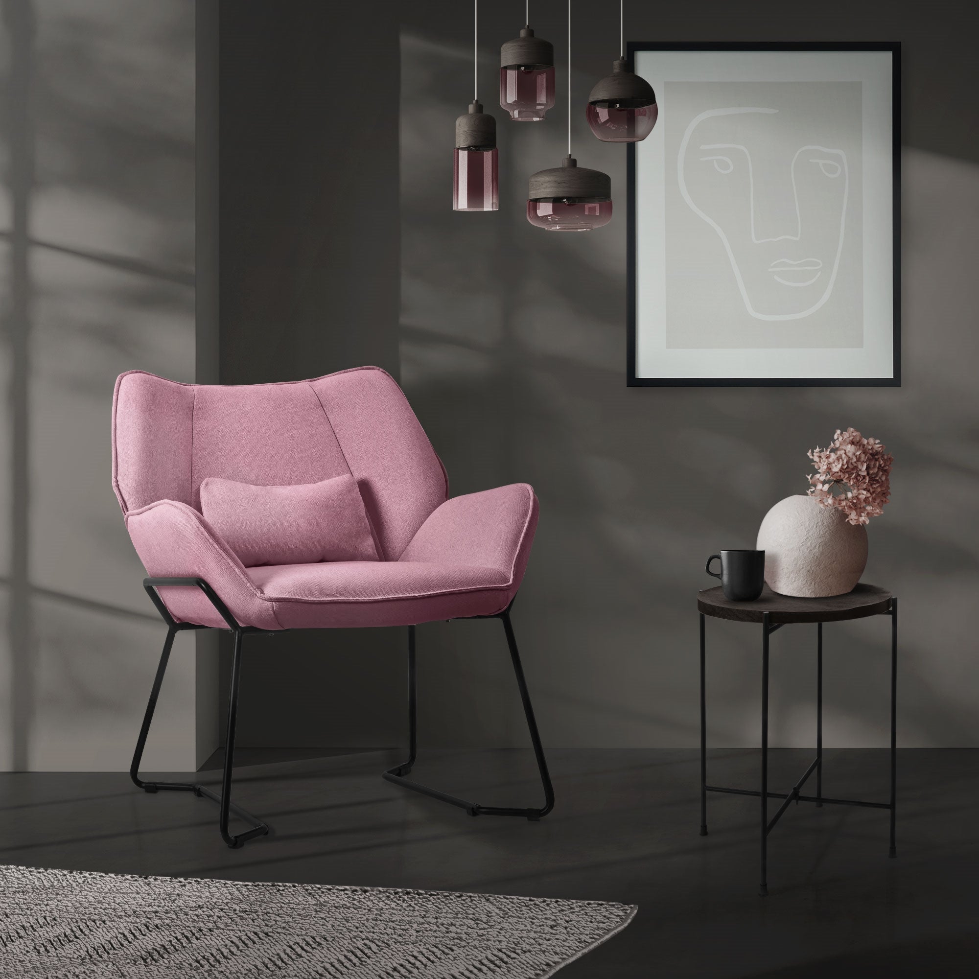 A pink chair with cushions in front of a wall and a picture.