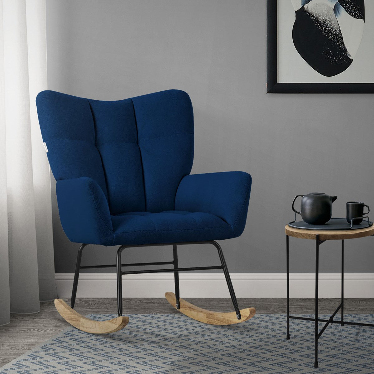 Blue rocking chair in a room with a table and teapot.