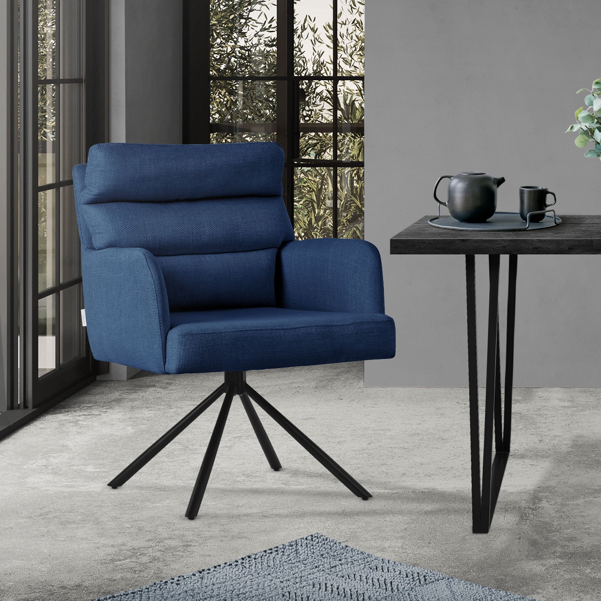 Blauer Sessel neben einem Tisch mit Teekanne und Tasse in einem Raum mit Fen
