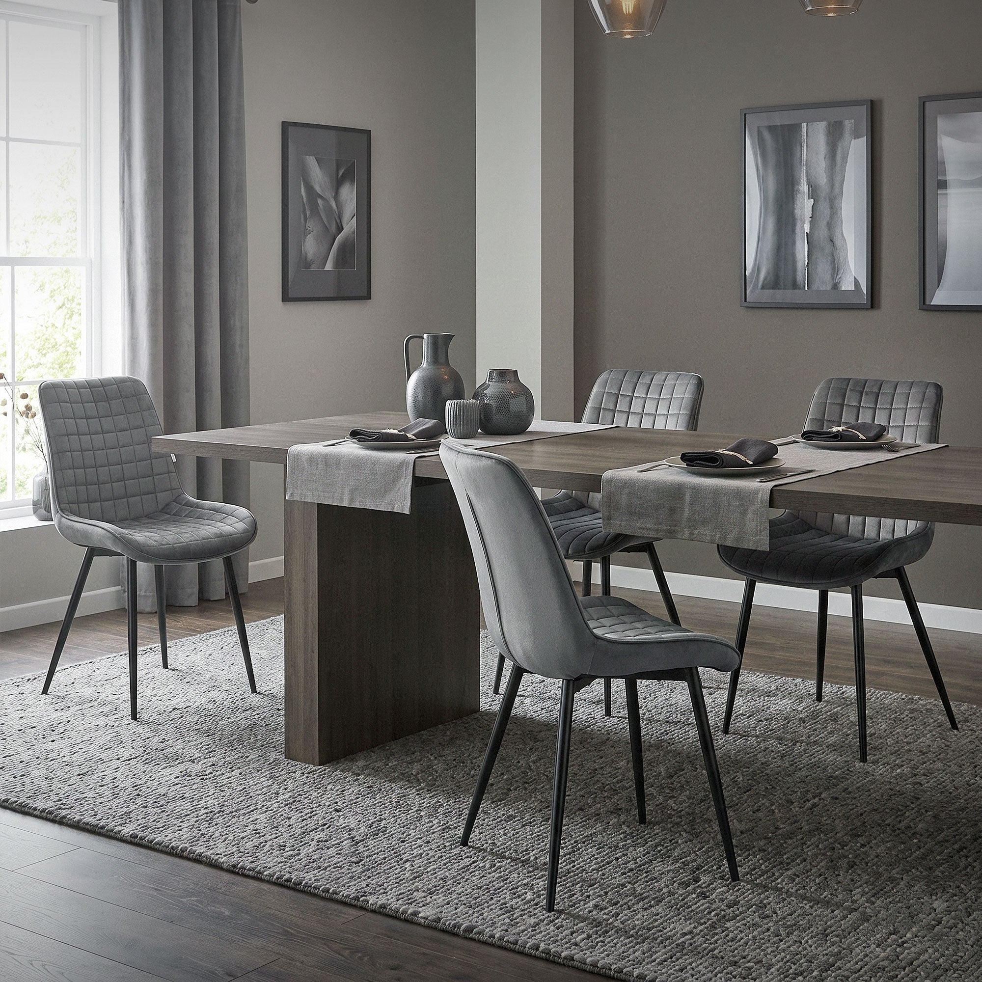 Ein Esszimmer mit einem großen Tisch, grauen Stühlen und dekorativen Bildern an der Wand.