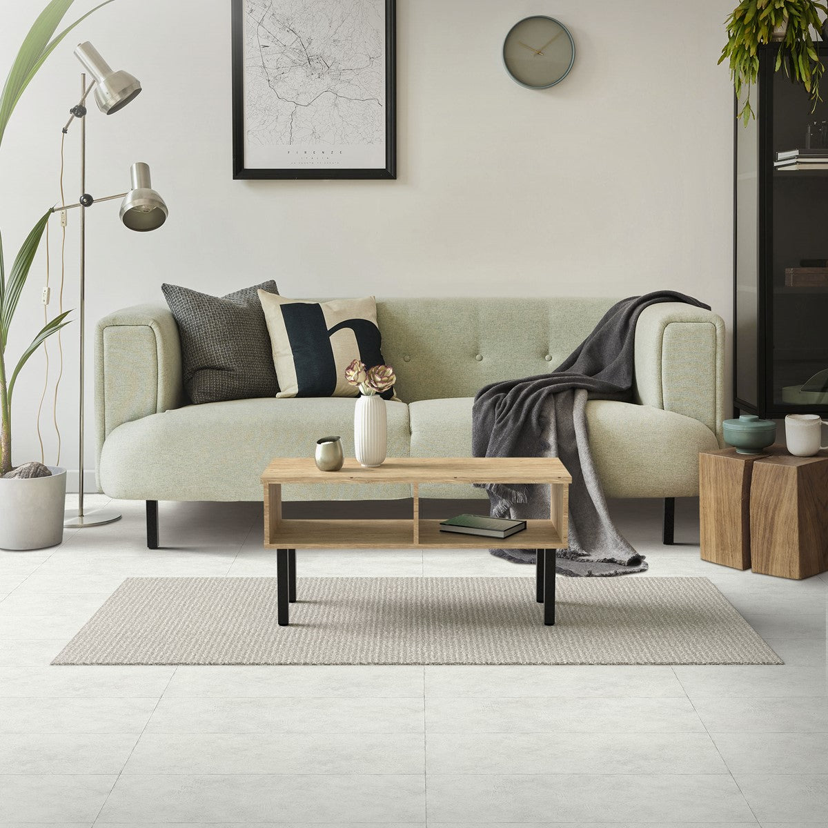 Couch mit Kissen und Decke, Tisch mit Vase, Wand mit Uhr und Bild.
