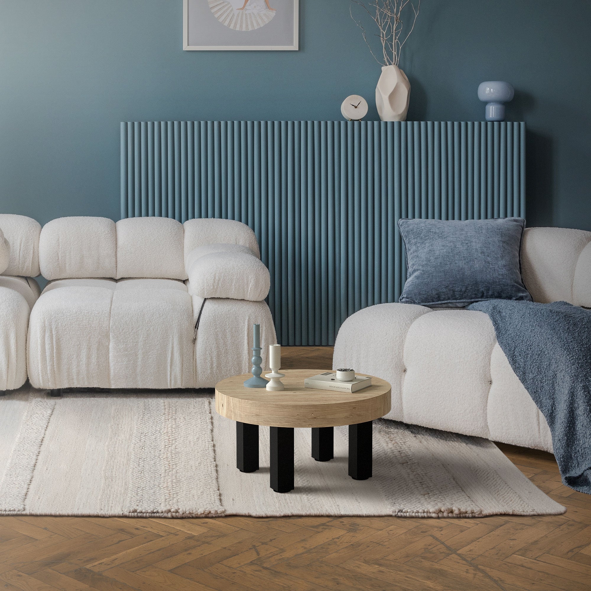 Zwei helle Sofas auf einem Teppich, runder Tisch in der Mitte, blaue Wand im Hintergrund.