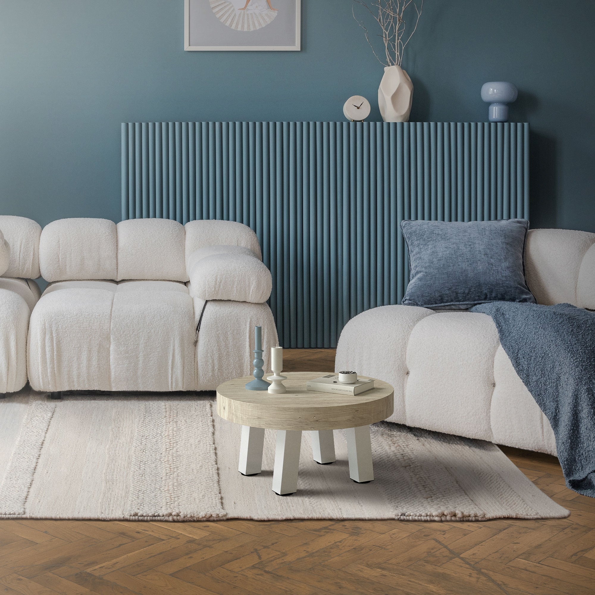 Living room with two light sofas, round table, and blue wall.
