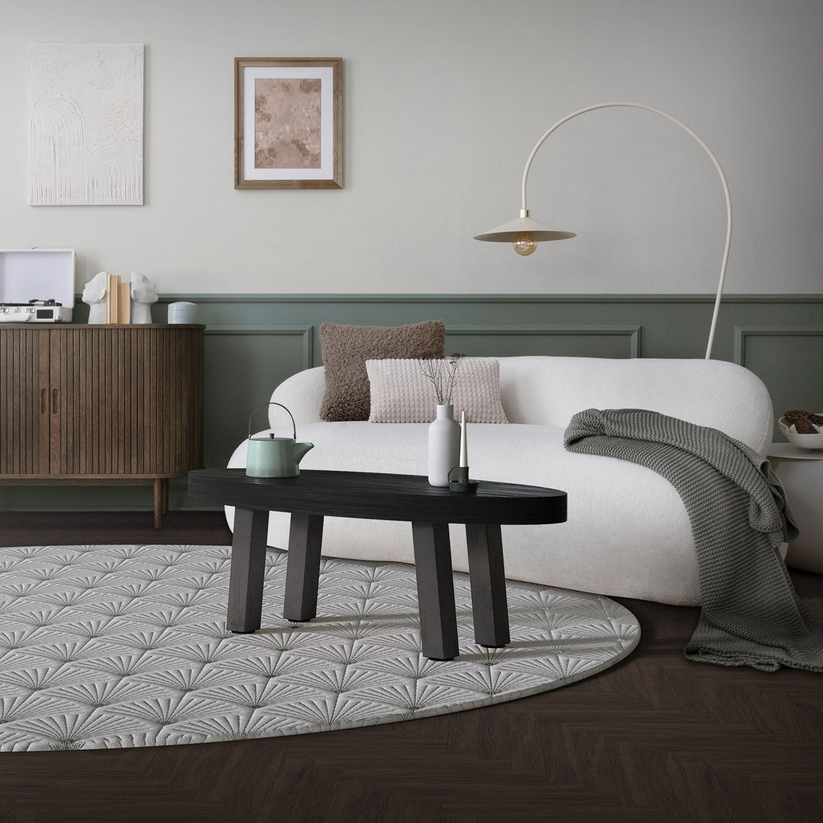 Wohnzimmer mit Sofa, Tisch und Dekoration auf einem runden Teppich.