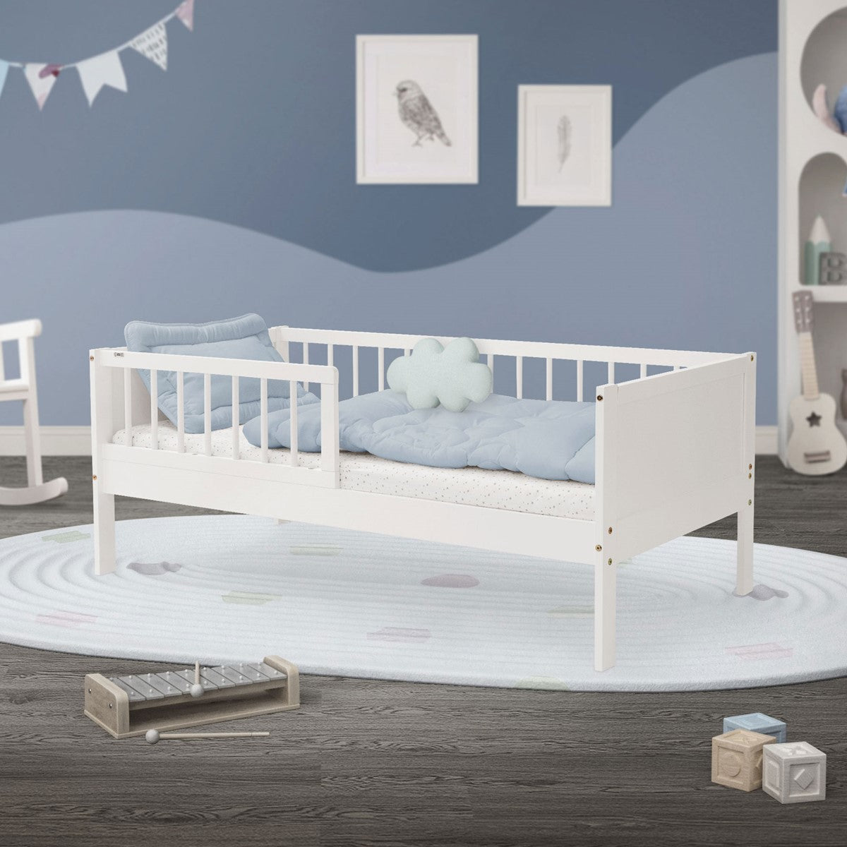 Cama infantil branca num quarto com uma parede azul e brinquedos.