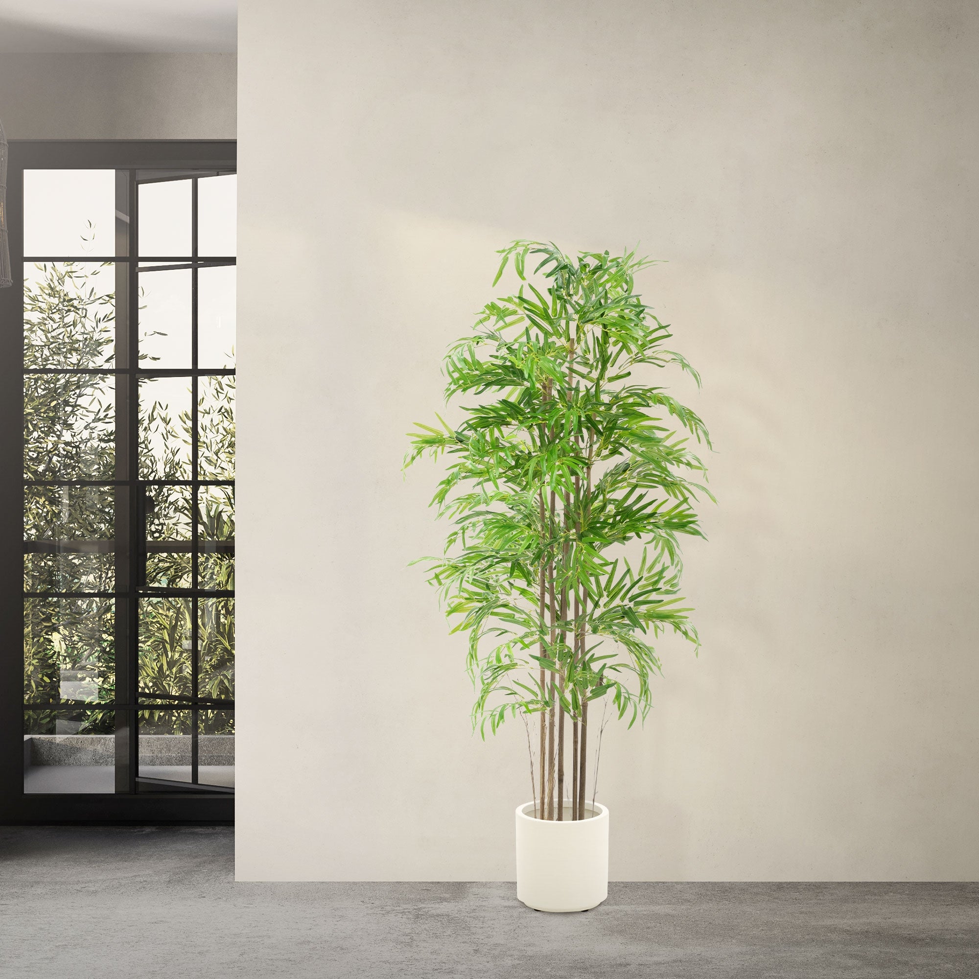 Albero artificiale in un vaso bianco davanti a una finestra.