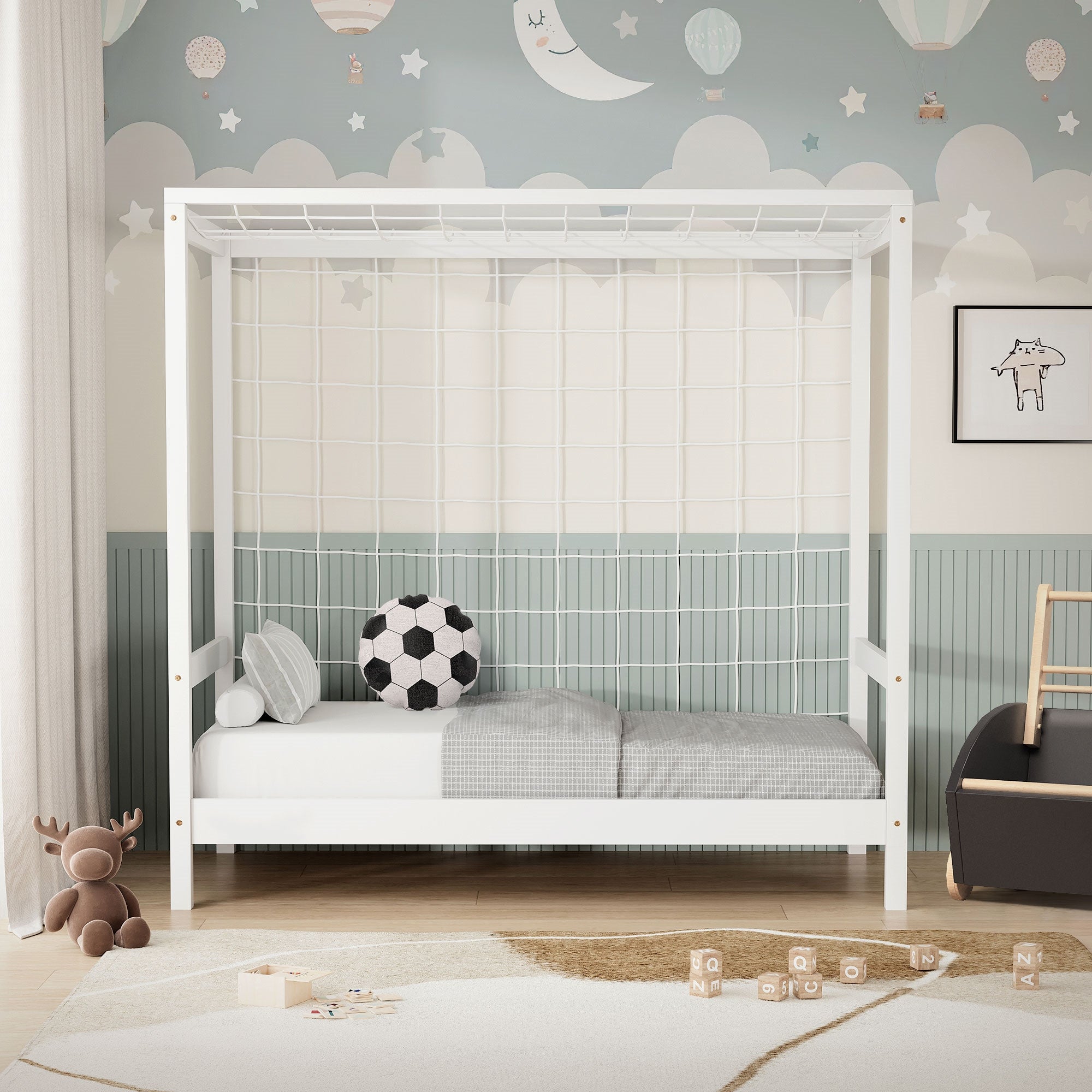 Ein Kinderbett mit Netz, Kissen und einem Fußball auf einer grauen Decke.