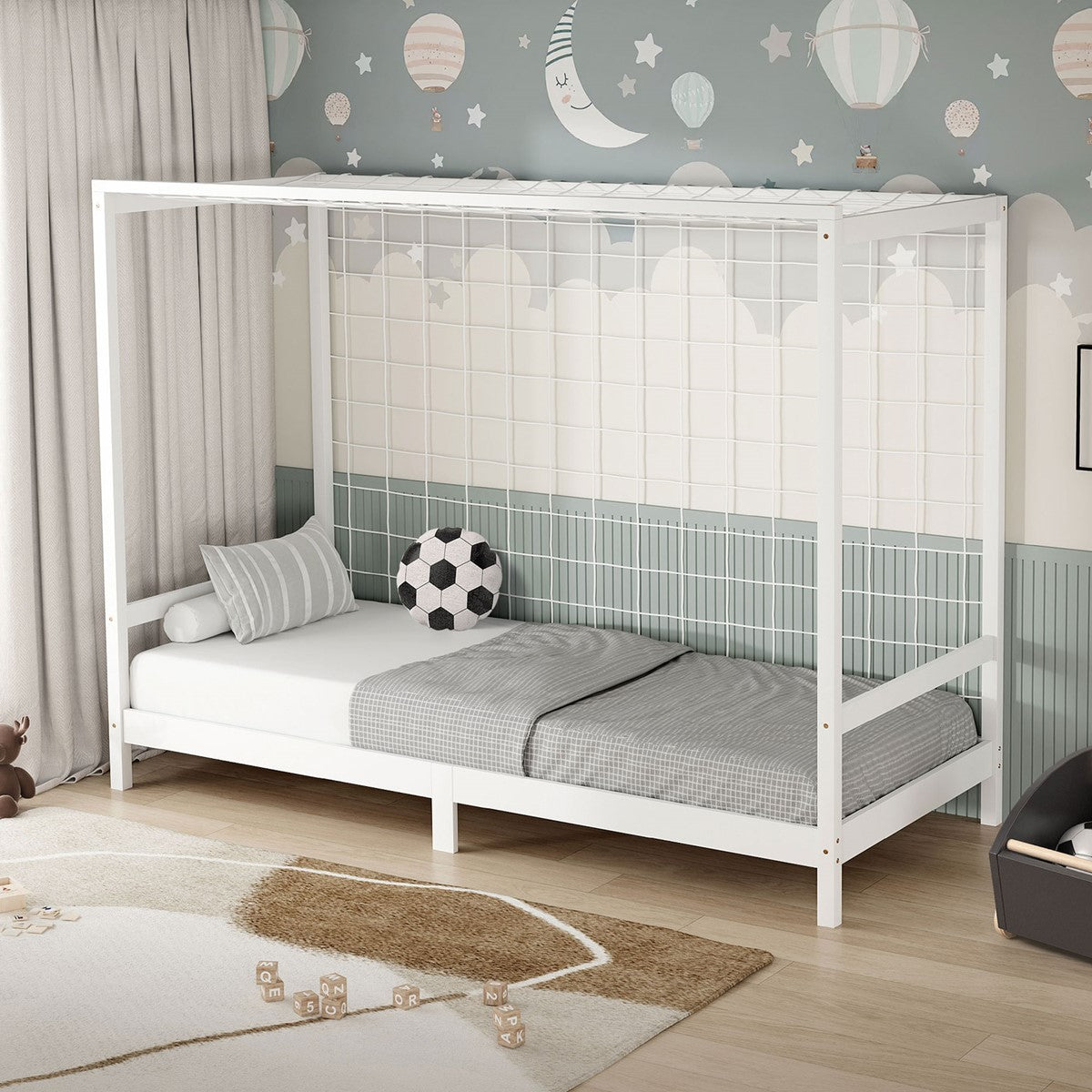 White wooden children's bed with bars, gray bedding, and a soccer ball on the bed.