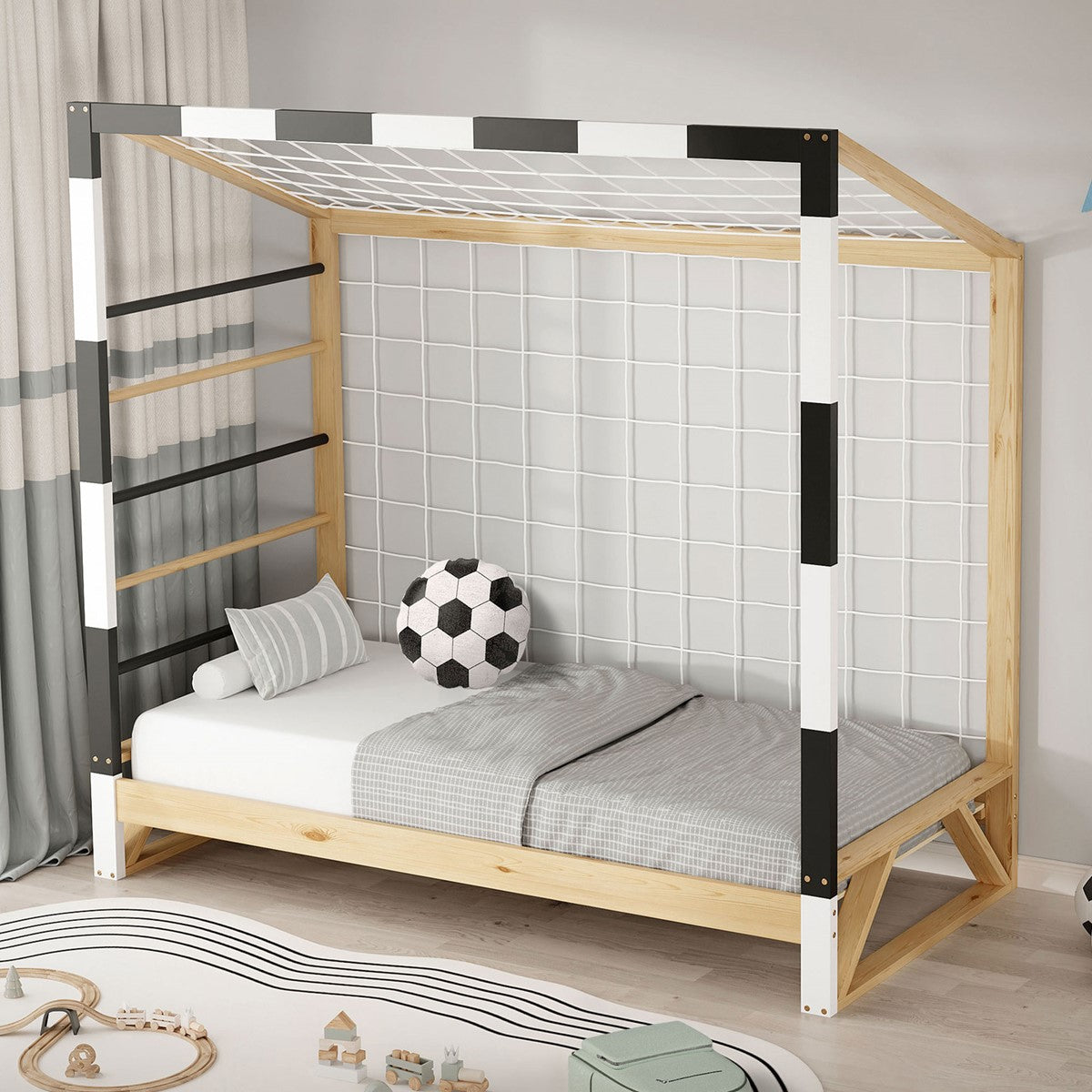 Un letto con un pallone da calcio e un lenzuolo grigio in una stanza luminosa.
