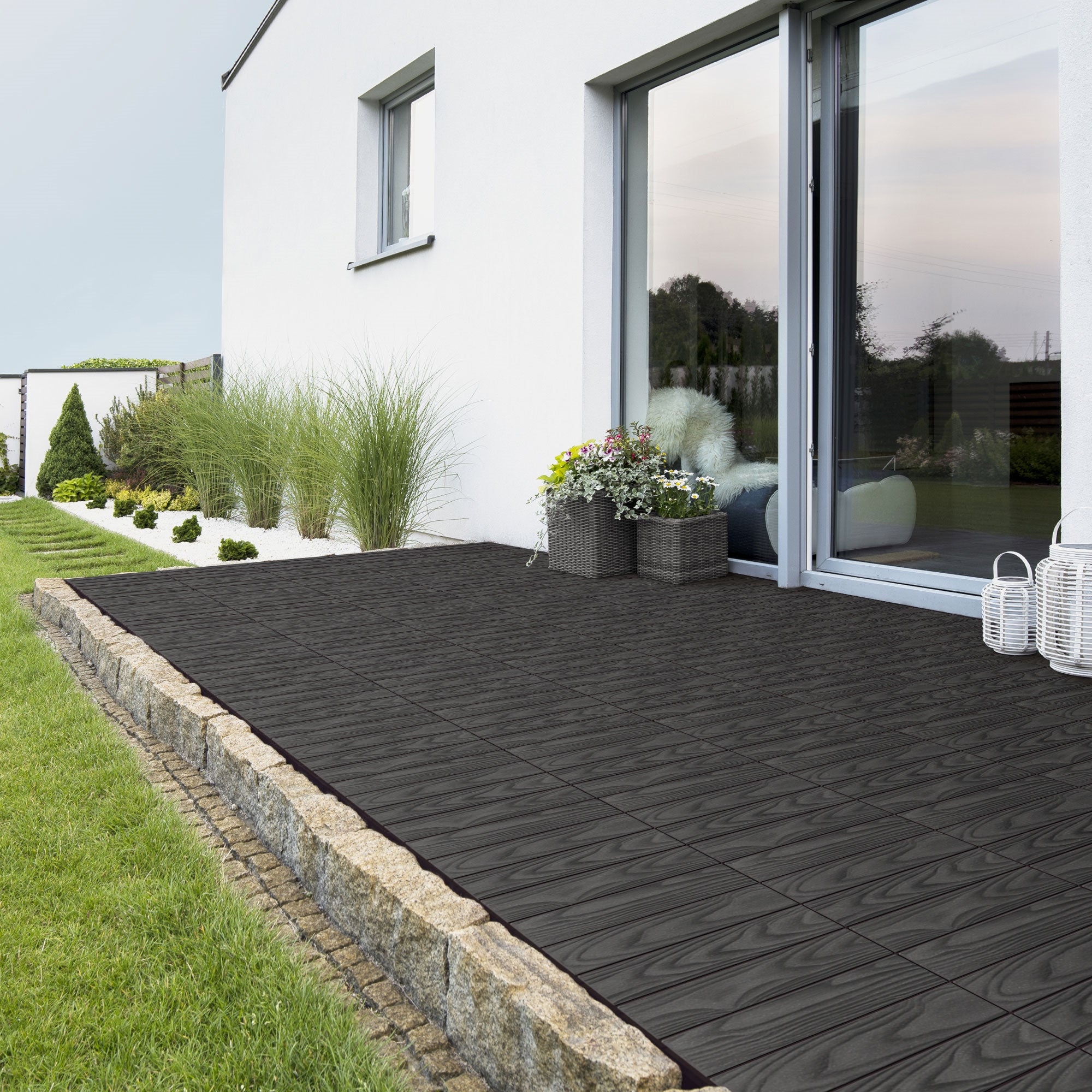 Terrasse mit verlegten Fliesen und Pflanzen.
