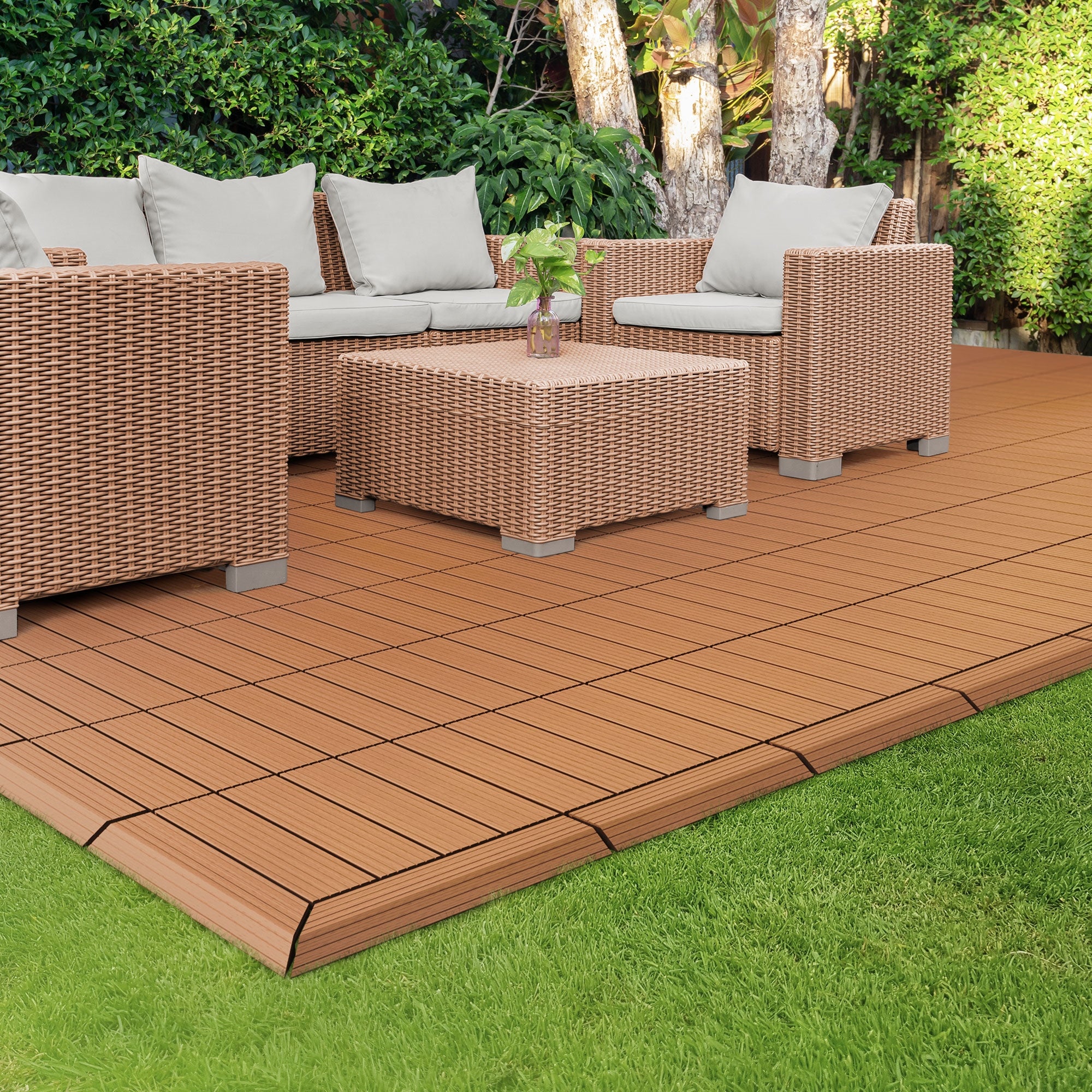 Sitzgruppe aus Rattan mit Kissen auf einer braunen Terrasse aus WPC-Platten.
