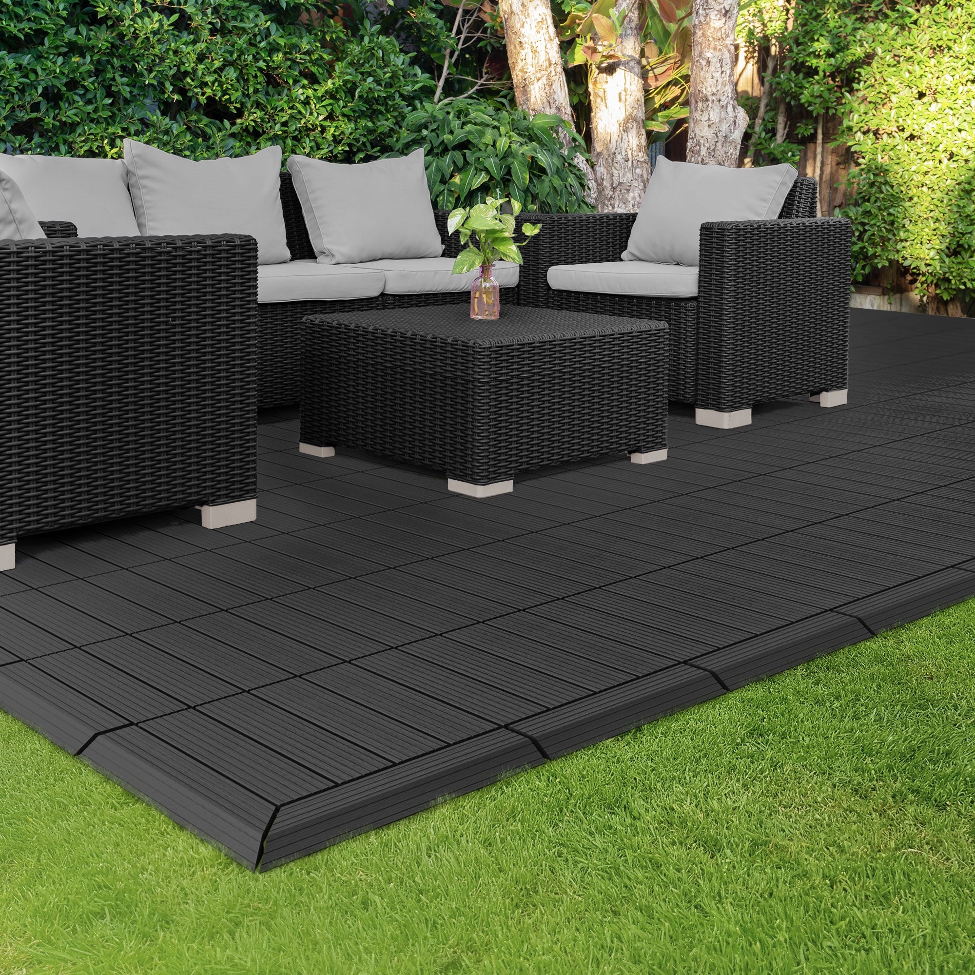 Seating group made of rattan with cushions on a black terrace made of WPC boards.