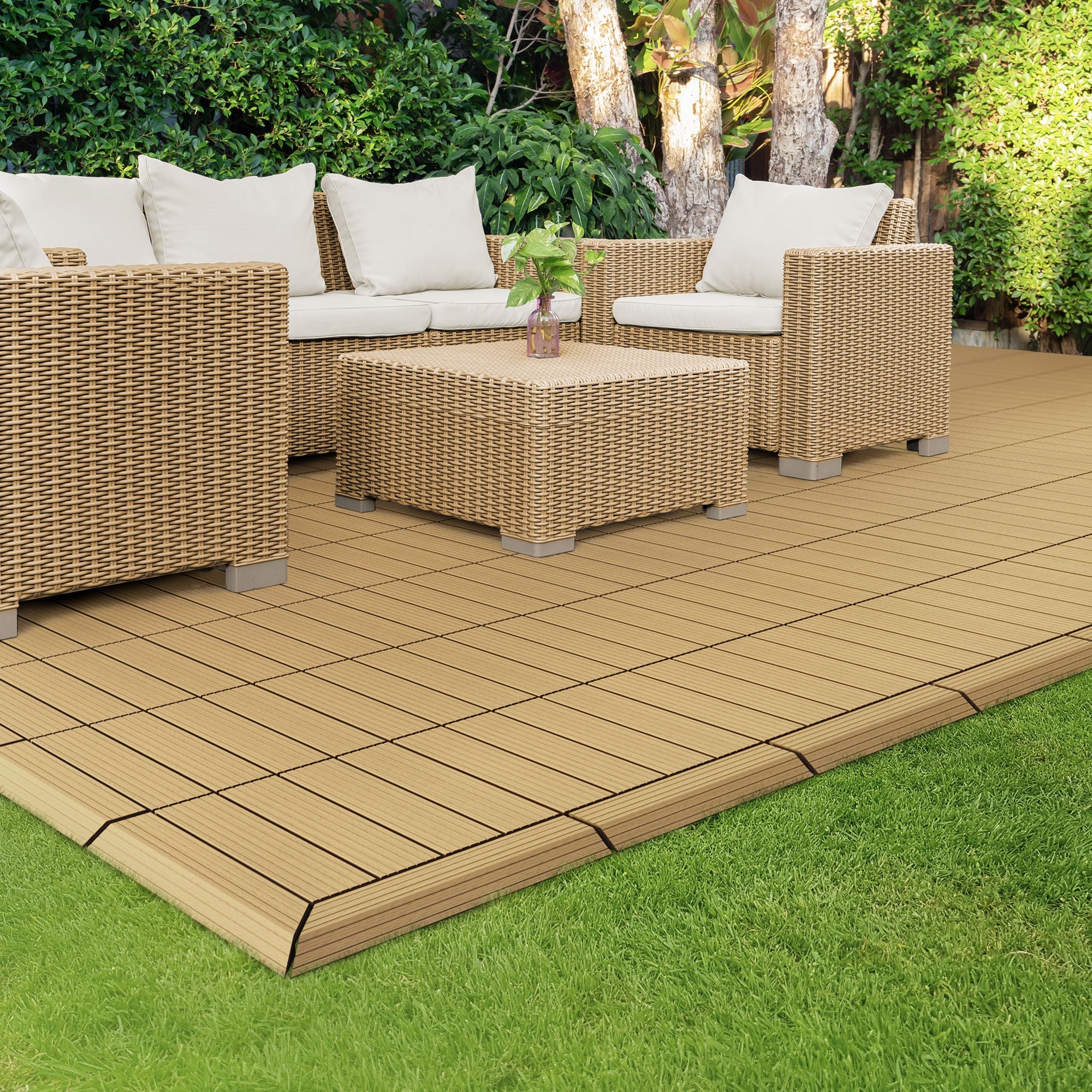 Sædegruppe af rattan med bord på en træterrasse, omgivet af planter.