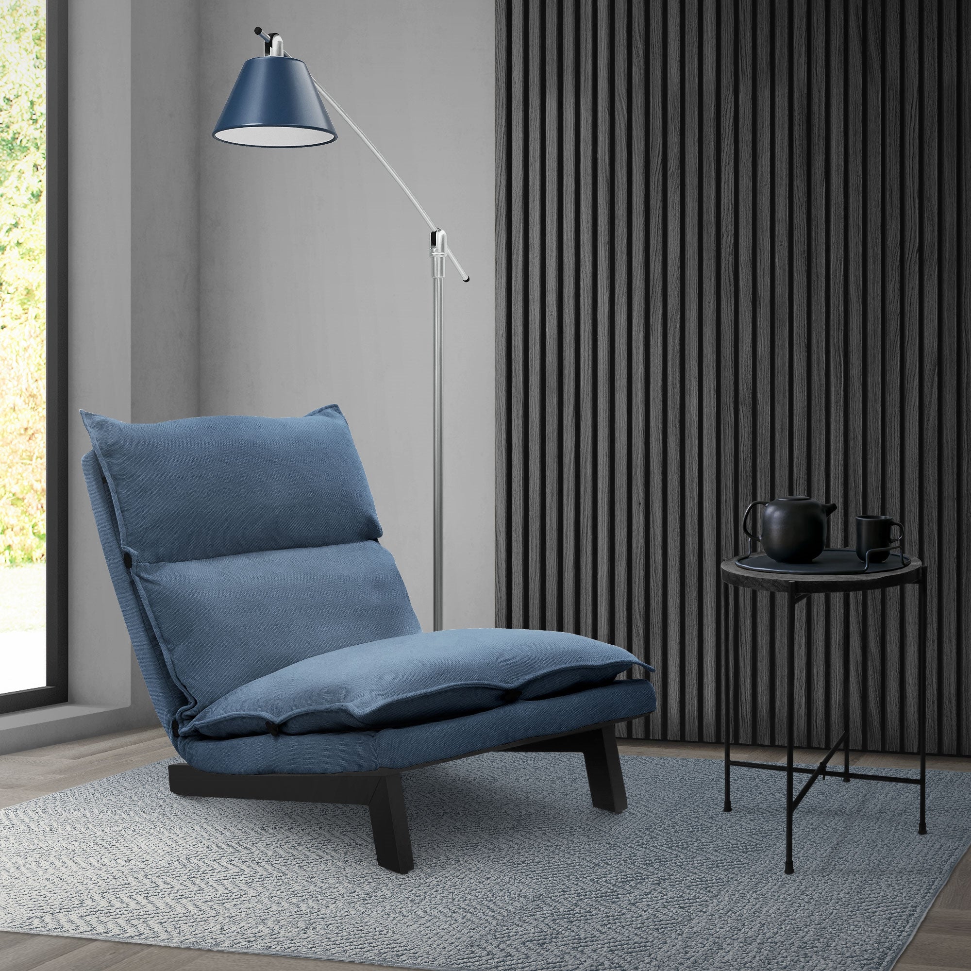 Sillón azul al lado de una lámpara de pie y una mesa pequeña.