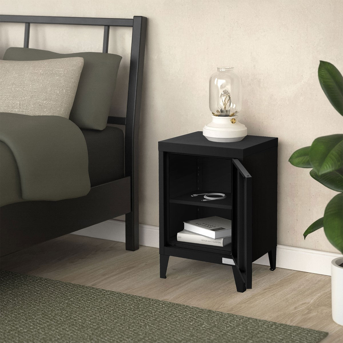 Mesita de noche negra junto a una cama, con una lámpara y objetos en el estante.