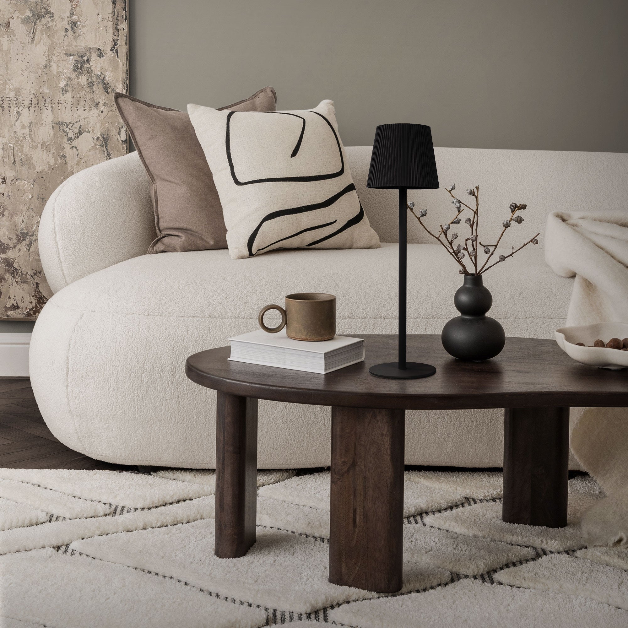 Salon avec lampe sur pied noire, table ronde en bois et canapé.