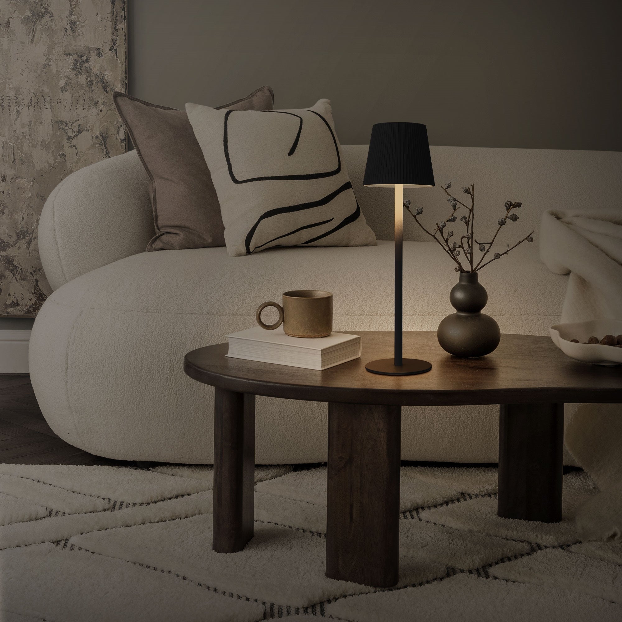 Un salon avec un canapé, une table, une lampe et un vase sur la table.