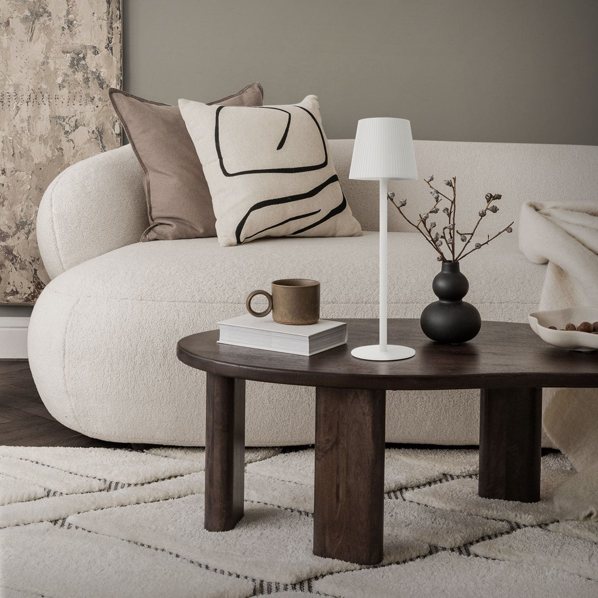 Obývacia izba s pohovkou, stolom, stojacou lampou a dekoráciou na stole.