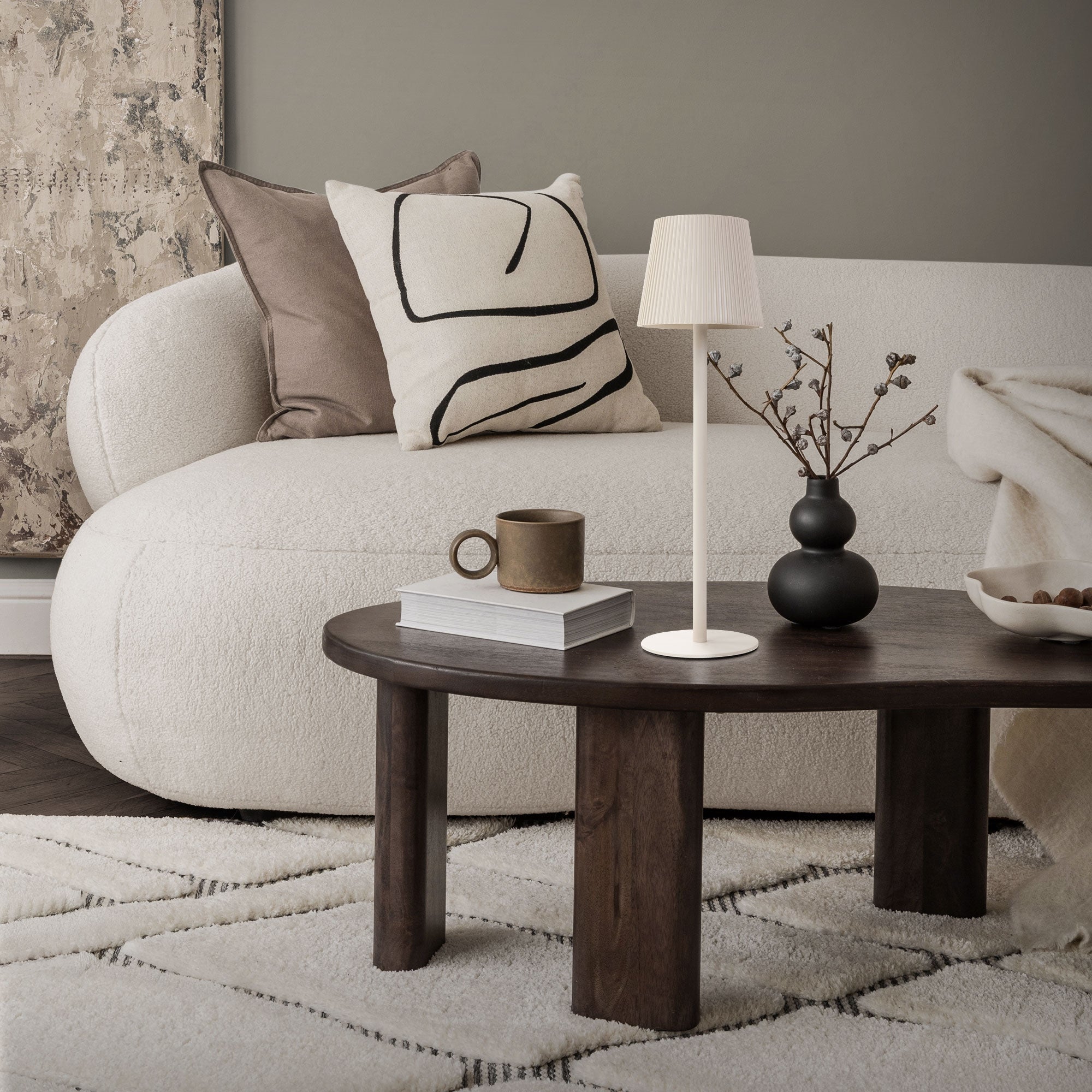 Living room with sofa, cushions, table, and lamp.